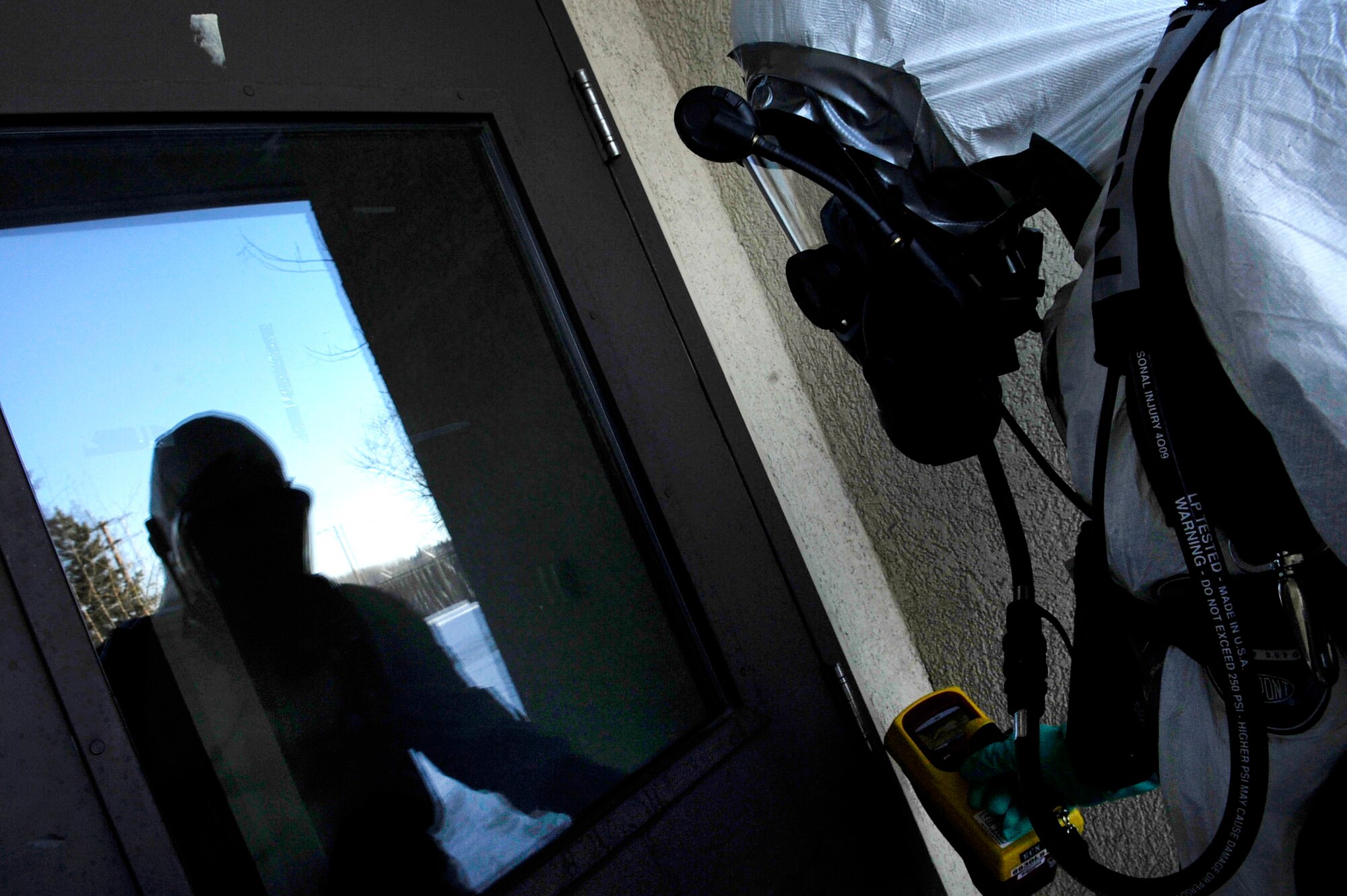 Senior Airman Donny Baker checks a door for hazardous substances after a mock suspicious package was found at the snow barn during an operational readiness exercise March 11, 2011, Eielson Air Force Base, Alaska. The exercise is designed to give Airmen experience in a simulated heightened threat environment. Airman Baker is a bio-environmental technician assigned to the 354th Medical Operations Squadron. (U.S. Air Force photo/Airman 1st Class Laura Goodgame)