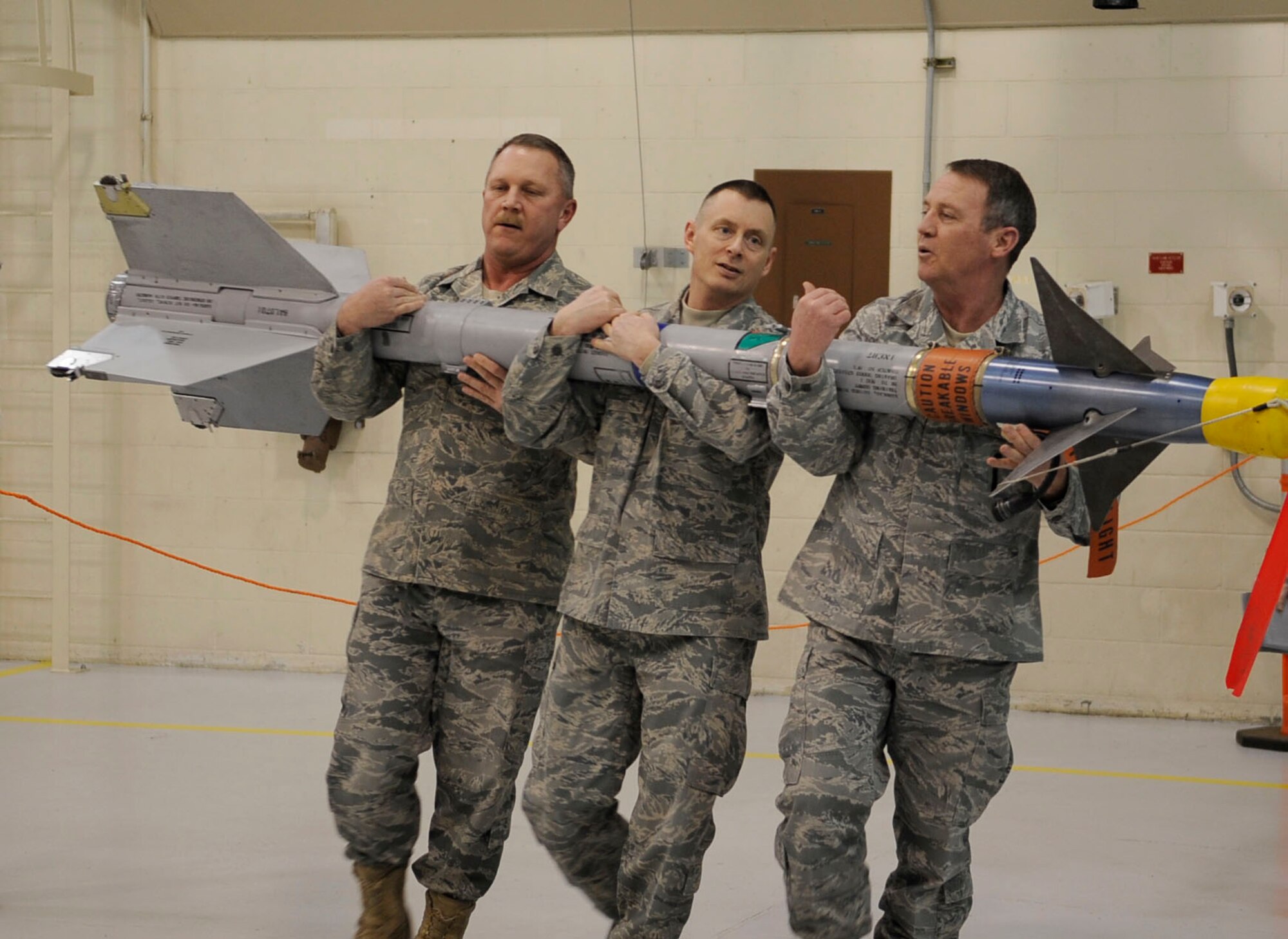 Chief Master Sgt. Dale Uden, Master Sgt. David Madison, and CMSgt.  Kevin Dolan off-load an AIM-9 L/M Sidewinder Missile from an F-16 Fighting Falcon during the annual load crew of the year competition March 11, 2011, Eielson Air Force Base, Alaska. The weapons shop senior enlisted leaders boosted moral among junior enlisted Airmen during the competition by showing they still have what it takes to off-load munitions.  Chiefs Uden  and Dolan, and Sergeant Madison are assigned to the 354th Aircraft Maintenance Squadron. (U.S. Air Force photo/Airman 1st Class Laura Goodgame)