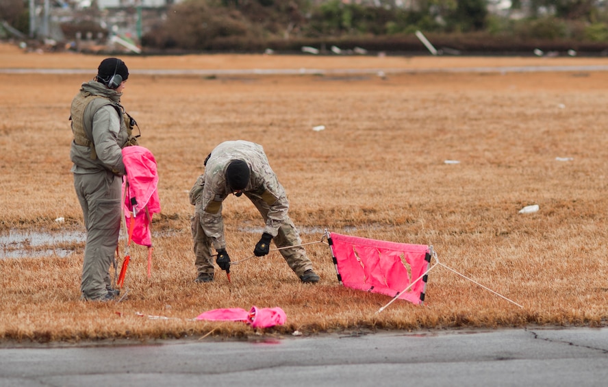 SENDAI AIRPORT, Japan -- Combat controllers from the 320th Special Tactics Squadron set up flightline markers to inform pilots of the useable space on the runway here March 16. Members of the 320th STS, stationed out of Kadena Air Base, deployed to Sendai Airport to help clear the runway and make it ready for fixed-wing aircraft traffic. (U.S. Air Force photo/Staff Sgt. Samuel Morse)