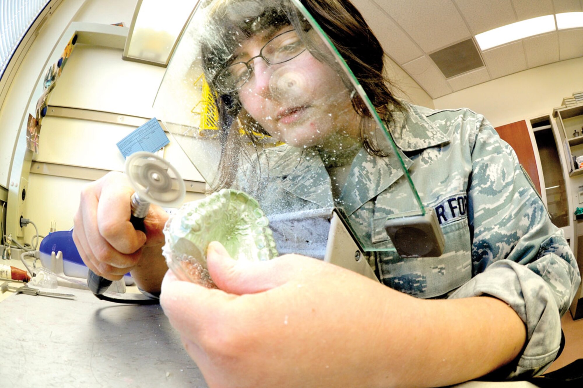 Air Force Staff Sgt. Sarah Rauch, a dental lab technician with the 673d Dental Squadron, cuts out a elastic mandibular advancement device from an impression March 3. The device is used to reposition the bottom jaw to allow a more open airway while sleeping.. (U.S. Air Force photo/Staff Sgt. Joshua Garcia)