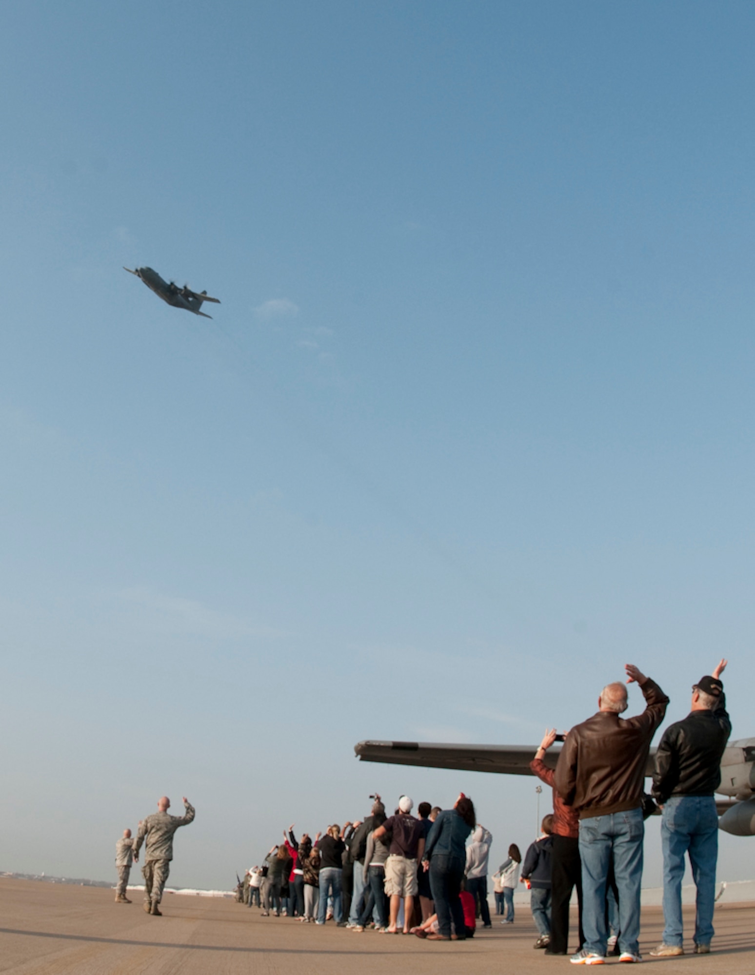 Family members and friends of the 136th Airlift Wing wave their final goodbyes to the C-130H above as they pass for their final fly-by before heading off to Afghanistan where they will spend a few months supporting Operation Enduring Freedom. The Wing deployed more than 140 personnel to support the operation. (U.S. Air Force photo by Senior Master Sgt. Elizabeth Gilbert/released)