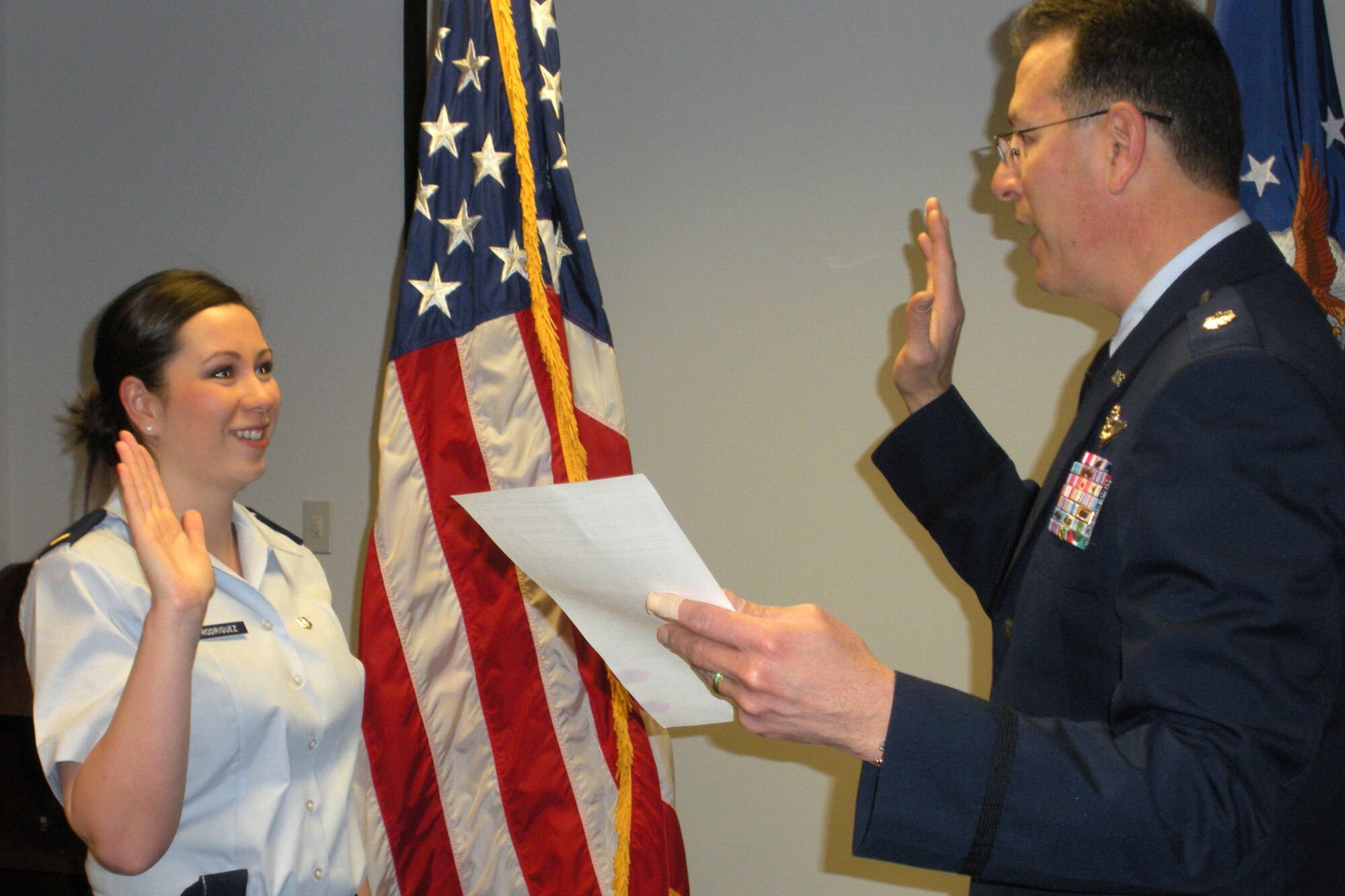 Lt. Col. Rafael Rodriguez, a B-52 radar navigator assigned to the 343rd Bomb Squadron at Barksdale Air Force Base, La., enlists his daughter 2nd Lt. Beverly S. Rodriguez, into the Air Force at the health recruiter's office in Arlington, Texas, Feb. 16, 2011. Lieutenant Rodriguez graduated as a registered nurse from Midwestern State University - Wichita Falls, Texas in Dec 2010, and is presently attending commissioning officer training (COT) at Maxwell, Air Force Base, Ala.  Following COT Lieutenant Rodriguez will attend a 10-week Air Force Nurse Training Program at Keesler Air Force Base, Miss., before reporting to the 96th Inpatient Operations Squadron at Eglin Air Force Base, Fla., where she will be assigned as a registered nurse. (Courtesy photo)