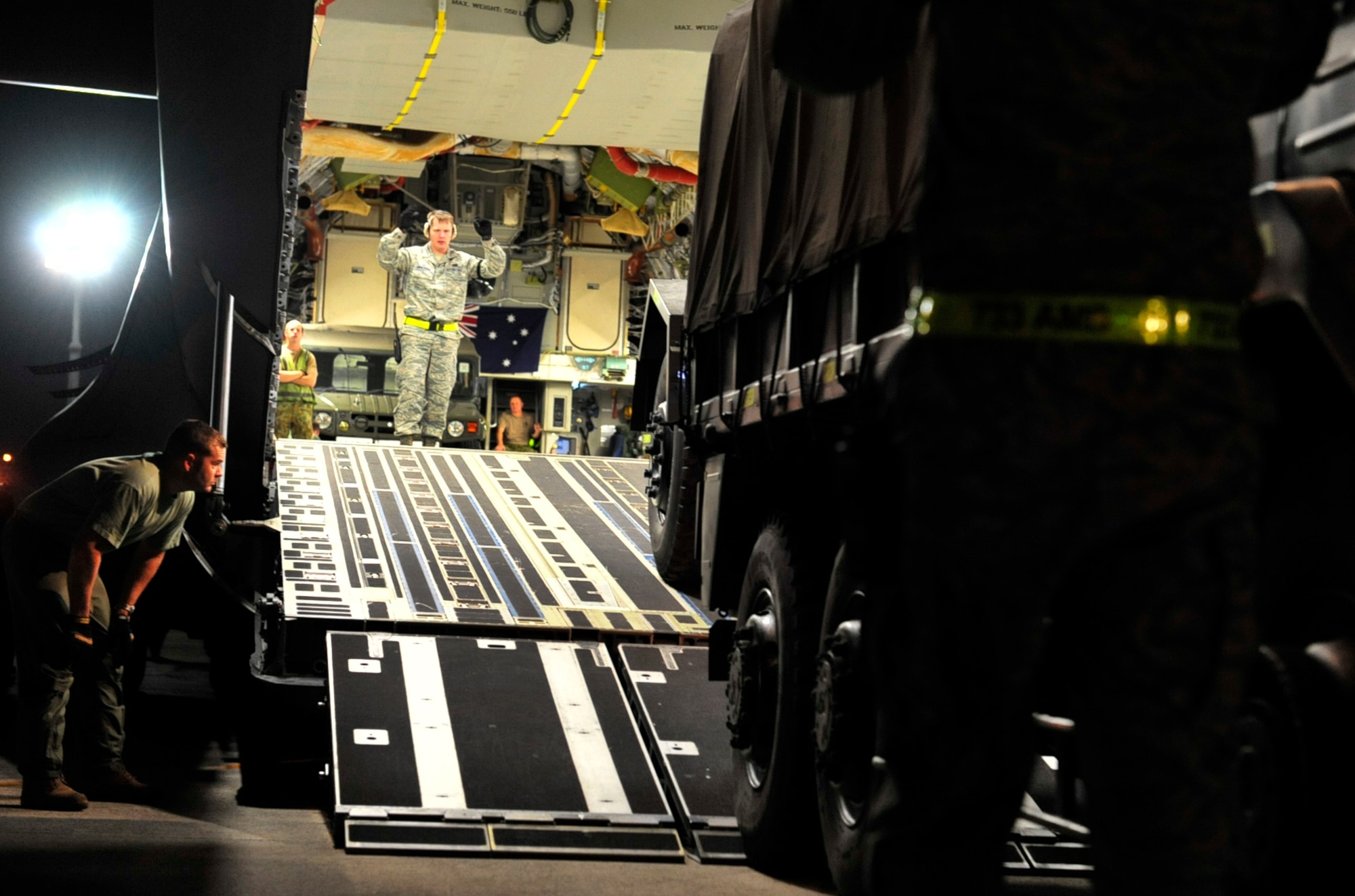 Senior Airman Andrew Ammerman, an Air Terminal Operations Center controller with the 733rd Air Mobility Squadron, guides a 15 Brigade, Japan Ground Self Defense Force truck onto a Royal Australian Air Force C-17 Globemaster III at Kadena Air Base, Japan, March 17. The truck was being loaded onto the aircraft, along with a team of JGSDF members and supplies to be sent to northern Japan in support of earthquake and tsunami relief efforts. (U.S. Air Force photo/Senior Airman Sara Csurilla)