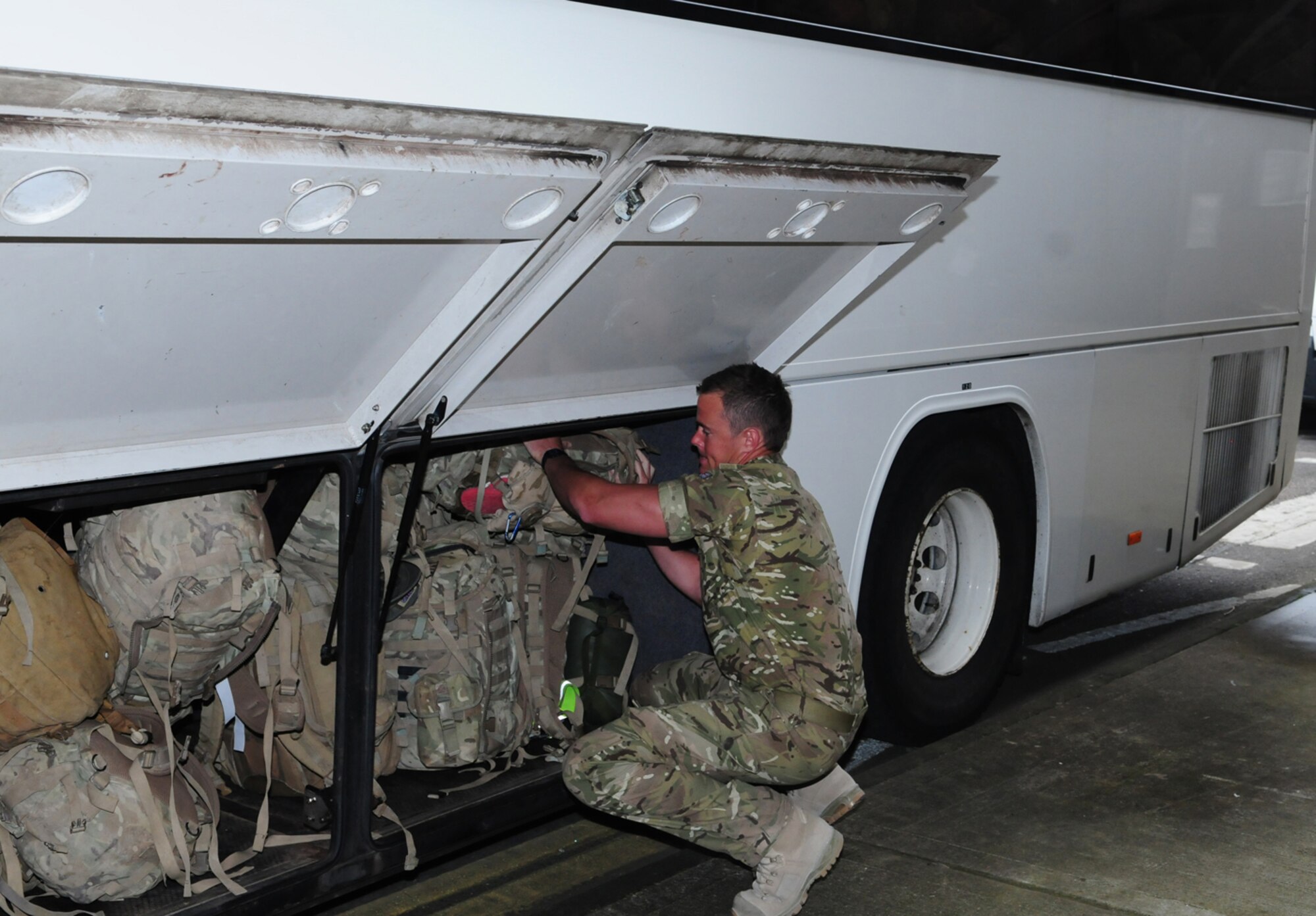 RAF MILDENHALL, England -- A British airman from 15 Squadron Royal Air Force Regiment, stows his backpack under a bus before he and other members of his squadron return home to their families at RAF Honington March 15, 2011. The squadron flew into RAF Mildenhall, rather than RAF Brize Norton, near Oxford, so they get home to their loved ones sooner. (U.S. Air Force photo/Karen Abeyasekere)