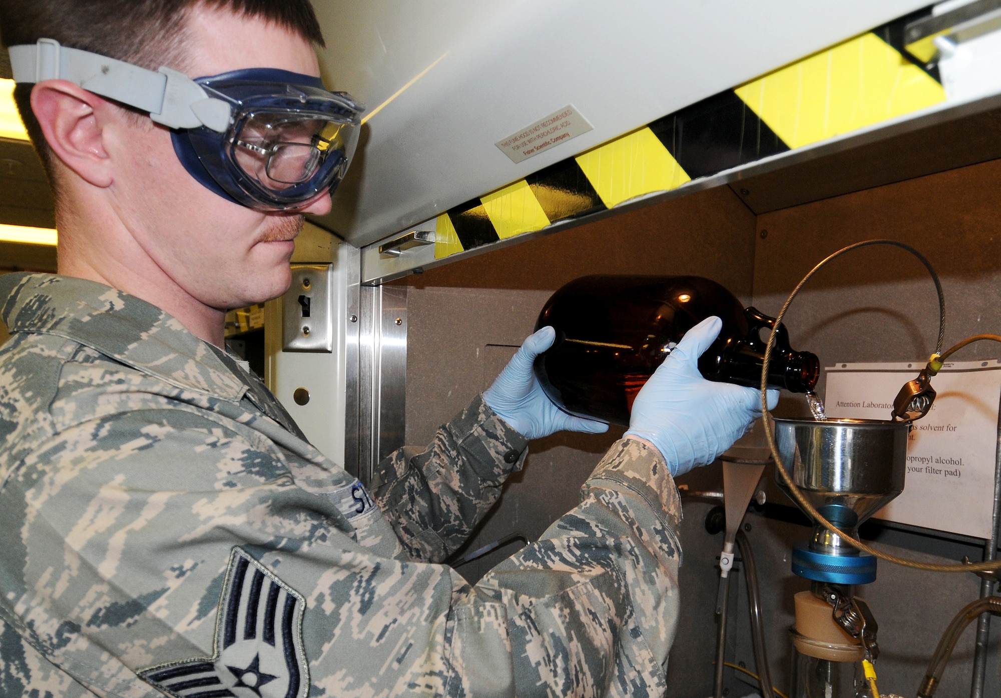 RAF MILDENHALL, England -- Staff Sgt. Jason Stump, 100th Logistics Readiness Squadron fuels laboratory technician, pours fuel through a filter as part of the "bottle method" here March 15, 2011.  The bottle method is used to test for solids in the fuel.  (U.S. Air Force photo/Senior Airman Tabitha M. Lee)