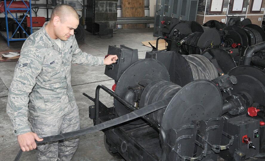 RAF MILDENHALL, England -- Airman 1st Class Vincent White, 100th Logistics Readiness Squadron forward area refueling point specialist, rolls up a hose after a preventative maintenance inspection on a forward-area movement cart. PMIs allow maintainers to catch minor discrepancies and prevent potentially costly or hazardous incidents to personnel or equipment.  (U.S. Air Force photo/Senior Airman Tabitha M. Lee)
