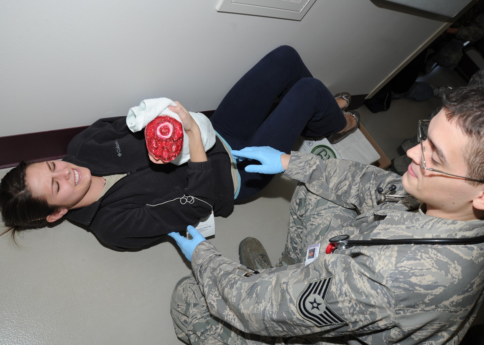 Tech. Sgt. Jesse Vargas, 384th Air Refueling Squadron independent duty medical technician, assists 1st Lt. Kimberly Waldo, 22nd Medical Operations Squadron nurse, with a mock wound during a tornado major accident response exercise at the base clinic March 10, 2011, McConnell Air Force Base, Kan. The MARE simulated a large number of victims from a tornado, preparing medical Airmen to deal with crisis scenarios. (U.S. Air Force photo/Senior Airman Maria A. Ruiz)