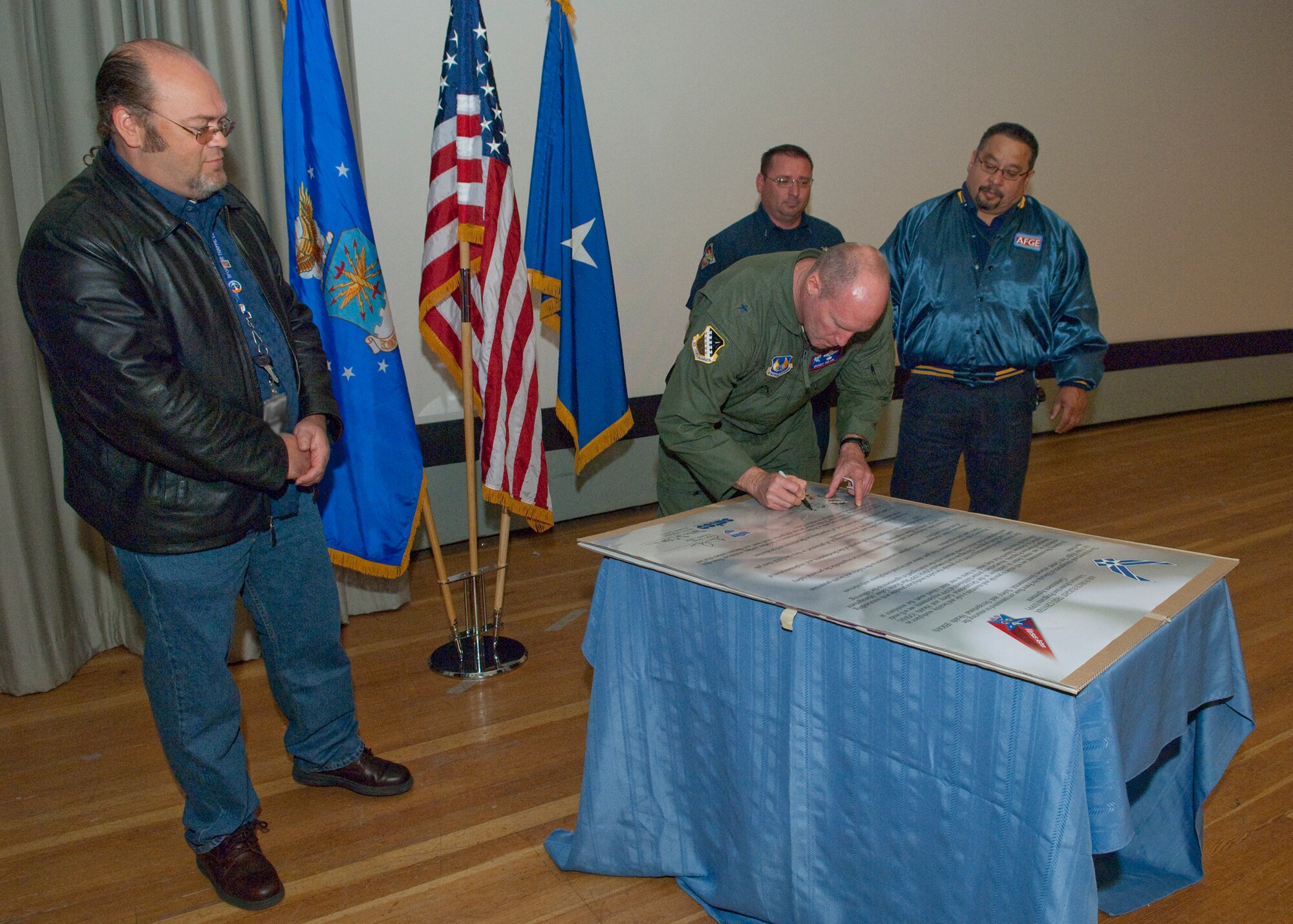 Brig. Gen. Robert C. Nolan II, Air Force Flight Test Center commander, signs the Voluntary Protection Program Agreement, as SPORT Air Traffic Controllers Organization base president Steven Oldebeken (left), International Association of Fire Fighters base president Braden Styles (right of center) and American Federation of Government Employees base president George Amaya (far right) wait to sign the document. The agreement establishes a partnership between management and the workforce to promote a safety culture around the base. (Air Force photo by Michael Yncera)