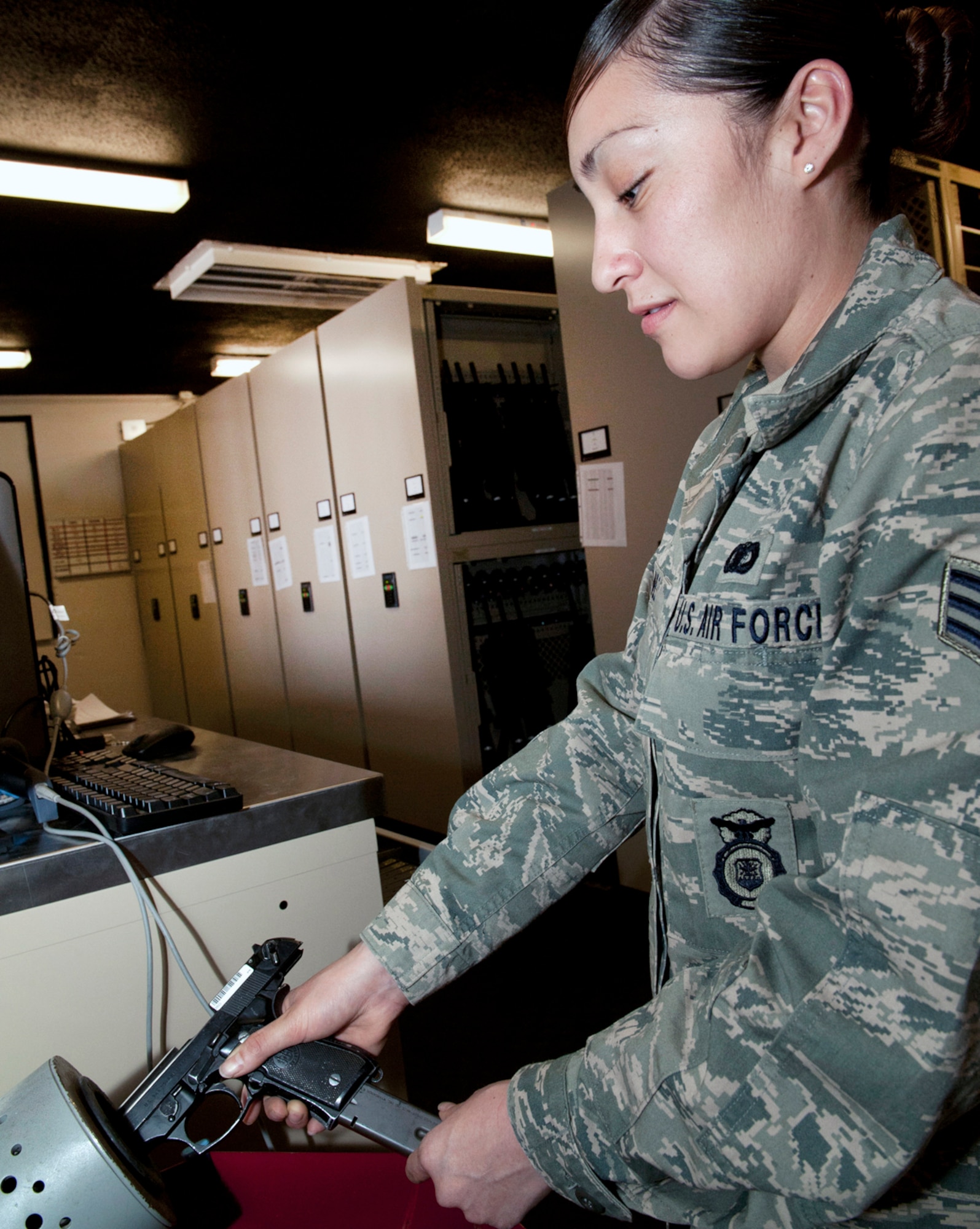 HOLLOMAN AIR FORCE BASE, N.M. -- Senior Airman Lorena Gomez, 49th Security Forces Squadron, clears an M-9 Baretta, March 14, 2011, at one of the armories here, before checking it out to another SFS member. Airman Gomez and other members of the armory check accountability of all M-4 carbines and M-9s issued to all security forces Airmen before each shift change. (U.S. Air Force photo by Senior Airman Veronica Stamps/Released)