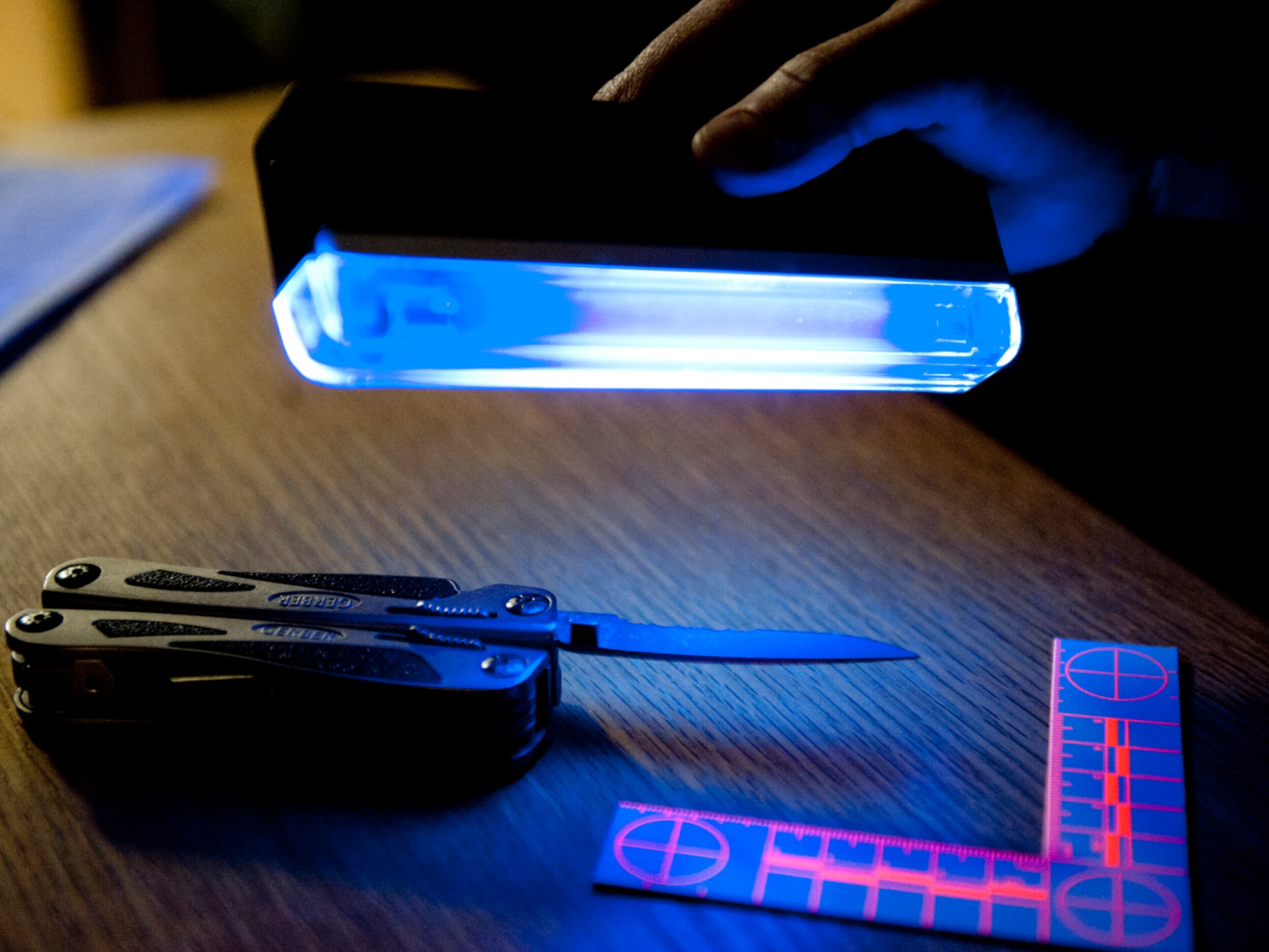 HOLLOMAN AIR FORCE BASE, N.M. -- Staff Sgt. David Myers, 49th Security Forces Squadron, demonstrates using alternative lighting, March 11, 2011, as a way to illuminate fingerprints on a weapon. SFS members investigate all crimes, offenses or incidents falling within their jurisdiction. These cases may involve coordination with federal, local or host-nation law enforcement agencies to complete a thorough investigation. (U.S. Air Force photo by Senior Airman Veronica Stamps/Released)