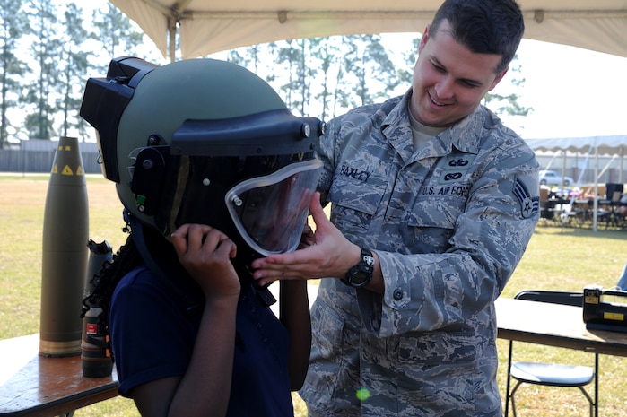 Senior Airman Johnathan Baxley helps Tanji Washington put on a helmet used for Explosive Ordinance Dispoal during the Annual Earth Day festival held at the picnic area on Joint Base Charleston, March 16. More than 700 fifth-grade children from around the Lowcountry attended the event which featured exhibits from the U.S. Fish and Wildlife Service, the South Carolina Department of Health and Environmental Control, the Charleston Soil and Water Conservation District and the Audubon Society. Airman Baxley is an Explosive Ordinance Disposal Technician assigned to the 628th Civil Engineering Squadron and Tanji Washington is a student at WB Goodwin Elementary. (U.S. Air Force photo/Staff Sgt. Nicole Mickle)