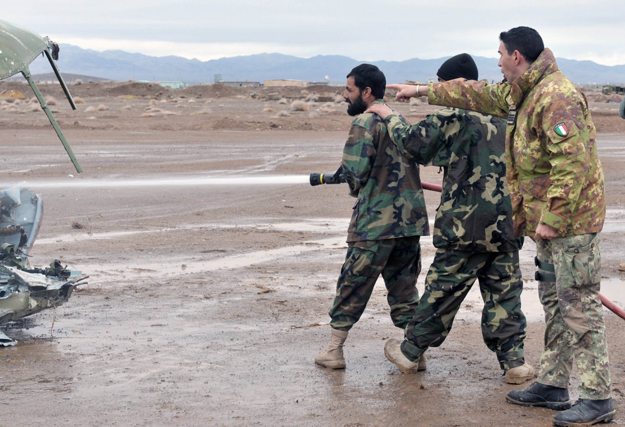 Italian air force 1st Marshall Ciro Tenace advises as Afghan airmen Abdull Fatho and Asis Ahmed extinguish a simulated helicopter crash March 6, 2011, at Shindand Air Base, Afghanistan. The airmen recently completed a four-month basic fire academy in Kabul. Marshall Tenace is an ITAF provider team adviser. (U.S. Air Force photo/Tech. Sgt. Kevin Wallace)
