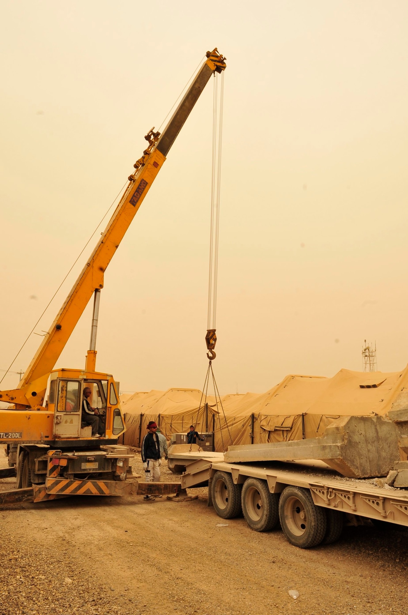 Not even a sand storm in the Iraqi desert stops the removal of concrete T-wall barriers at Victory Base Complex in Baghdad, March 3, 2011. The U.S. Government has turned over 80 installations and facilities to the Government of Iraq under the current security agreement. On this day an orange haze covers the contractors as they work. Each T-wall weighs 6 tons and is 12-feet tall, requiring a 10 to 20 ton crane to move them. (U.S. Air Force photo by Senior Master Sgt. Larry Schneck)
