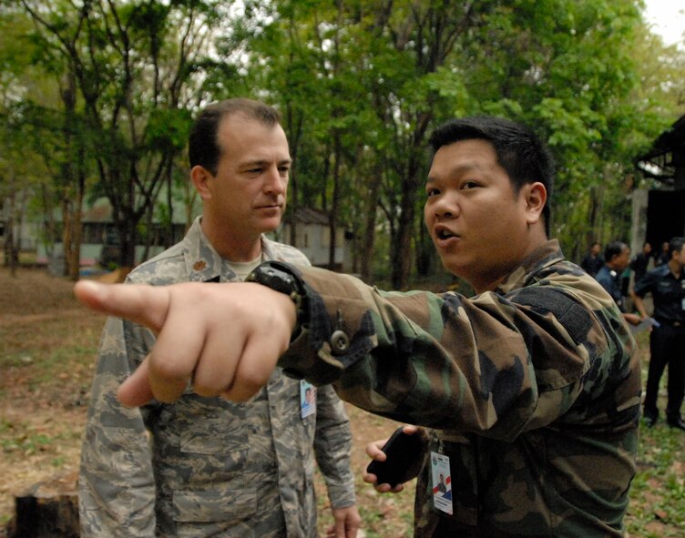 KORAT, Thailand - Maj. Jon Duncan, Joint U.S. Military Assistance Group air operations officer and regional area strategist for Thailand, and Flight Surgeon 3rd Class Warakorn Songsang from the Royal Thai Air Force discuss the arrival of the official party at a community outreach event at Ang Huai Yang School in Korat, Thailand, March 16. Major Duncan is a liaison officer for participants in Cope Tiger 2011, an annual, multilateral, joint field training exercise currently being conducted at Korat and Udon Thani Royal Thai Air Bases March 14 through 25. (U.S. Air Force Photo/ Capt. David Herndon)