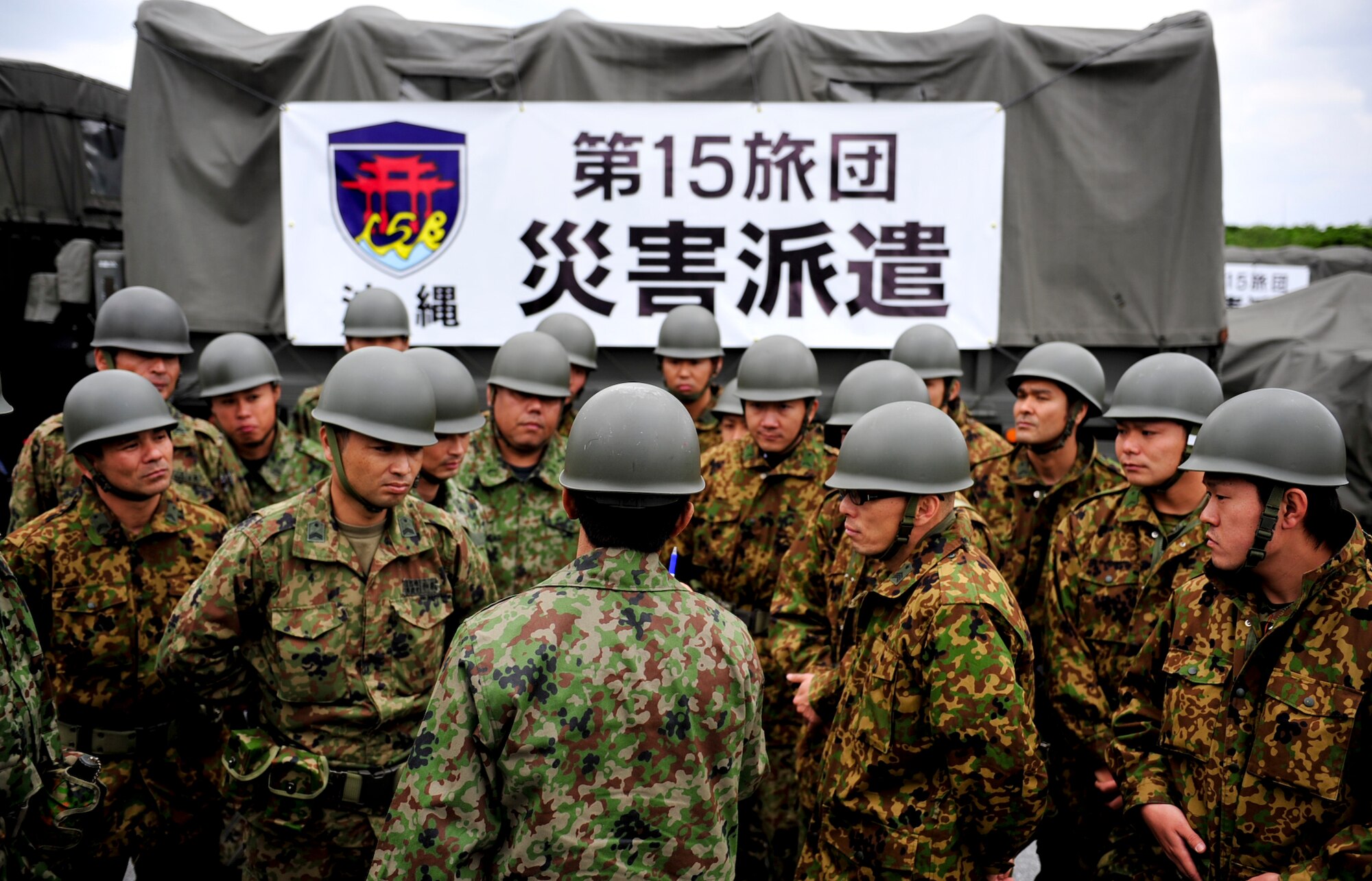 A team from the 15 Brigade, Japan Ground Self Defense Force, gathers for instruction before heading to mainland Japan March 16. Teams from the 15 Brigade, JGSDF along with thousands of pounds of supplies are departing from Kadena for northern Japan to aid earthquake and tsunami victims. Hundreds of Airmen, thousands of pounds of relief supply and many U.S. aircrafts have been sent to northern Japan from Kadena as well. (U.S. Air Force photos/Senior Airman Sara Csurilla)