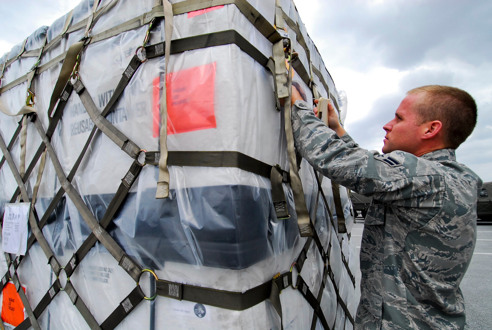 Airman 1st Class Neal Phillips with the 733rd Air Mobility Squadron prepares cargo full of supplies including clothes, blankets and toiletries to send with members of the 15 Brigade, Japan Ground Self Defense Force to mainland Japan March 16. Teams from the 15 Brigade, JGSDF along with thousands of pounds of supplies are heading to northern Japan to aid earthquake and tsunami victims. (U.S. Air Force photos/Airman 1st Class Maeson Elleman)