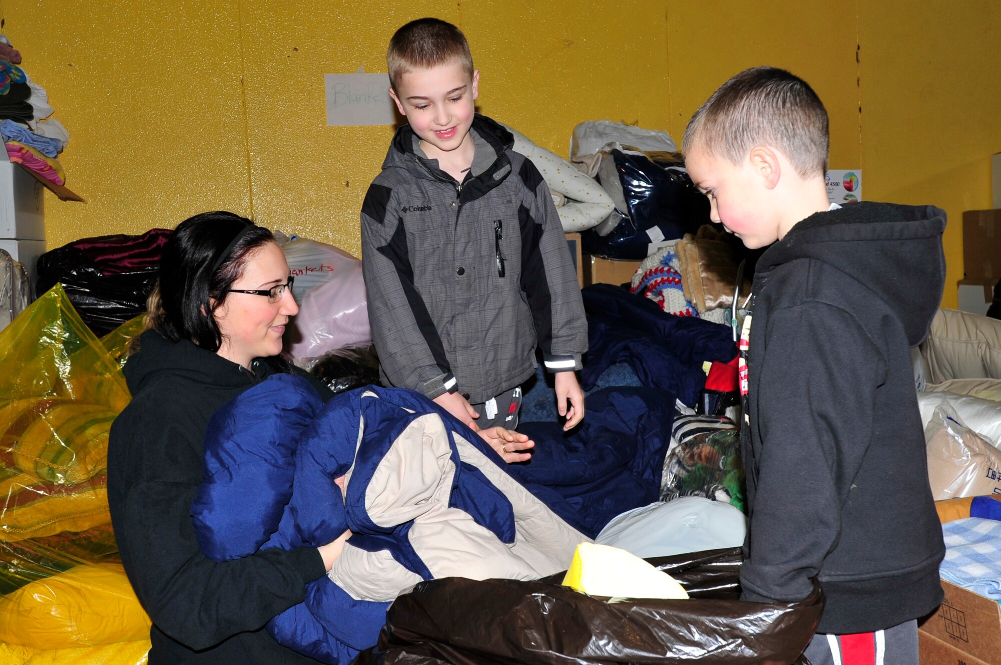 MISAWA AIR BASE, Japan -- Danielle, Eddie and Cameron Schwab, sort through donated items at Edgren High School Mar. 15. Bags and boxes of clothes, jackets, blankets and food were donated to help with relief efforts in areas affected by last Friday's earthquake and tsunamis. (U.S. Air Force photo by Staff Sgt. Marie Brown\Released)