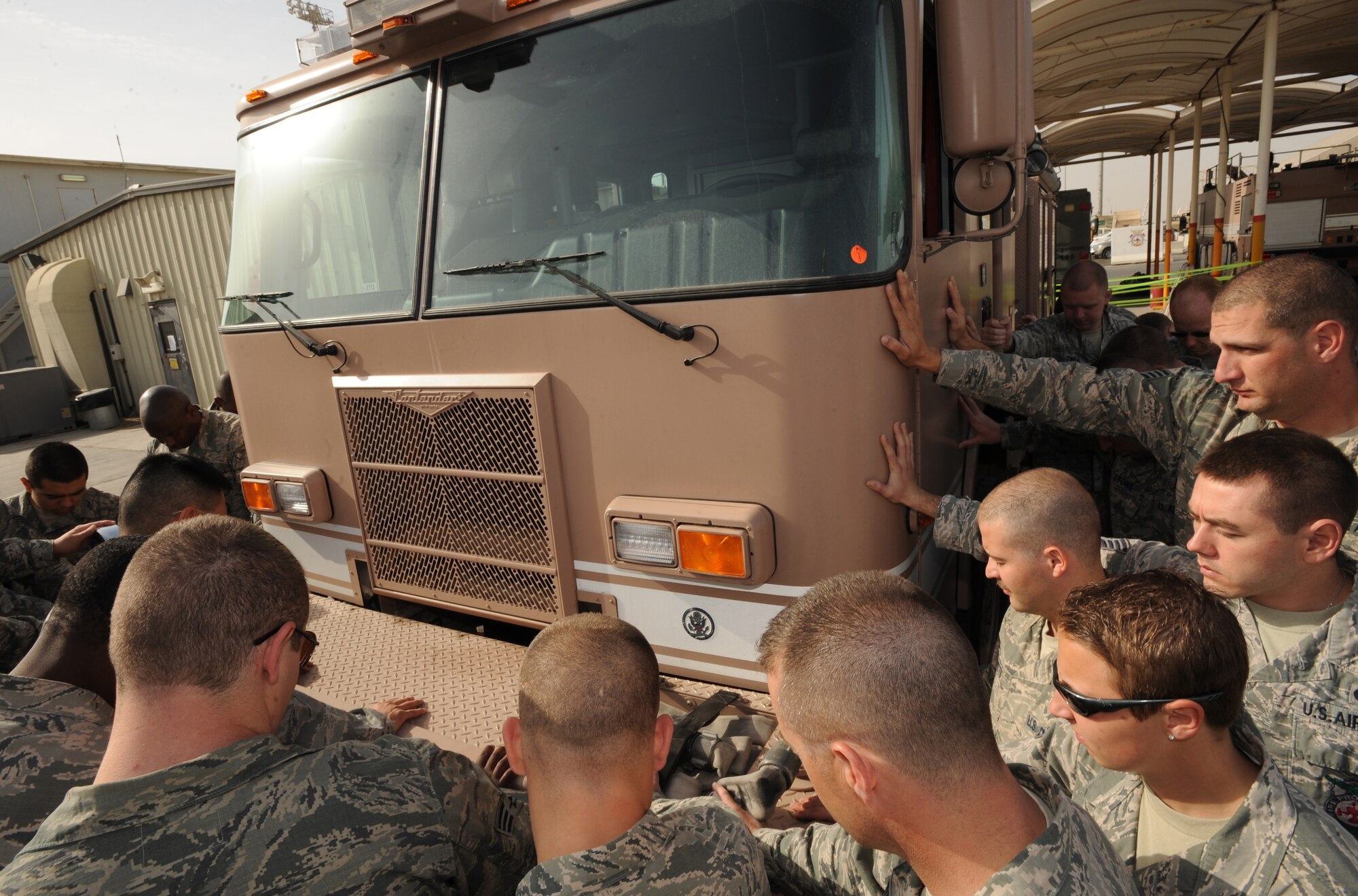 Members of the 380th Expeditionary Civil Engineer Squadron fire fighters lay their hands on the newest addition to Station 1 as Chaplain (Capt.) John Choi, 380th Expeditionary Air Expeditionary Wing, prays over it Mar. 8, 2011, during the Fire Station's Housing Truck Ceremony. Housing a new fire truck has been a tradition among fire fighters since a motorized truck replaced the fire brigades' horse-drawn water wagons in the 1800s. (U.S. Air Force photo by Senior Airman Maynelinne De La Cruz)
