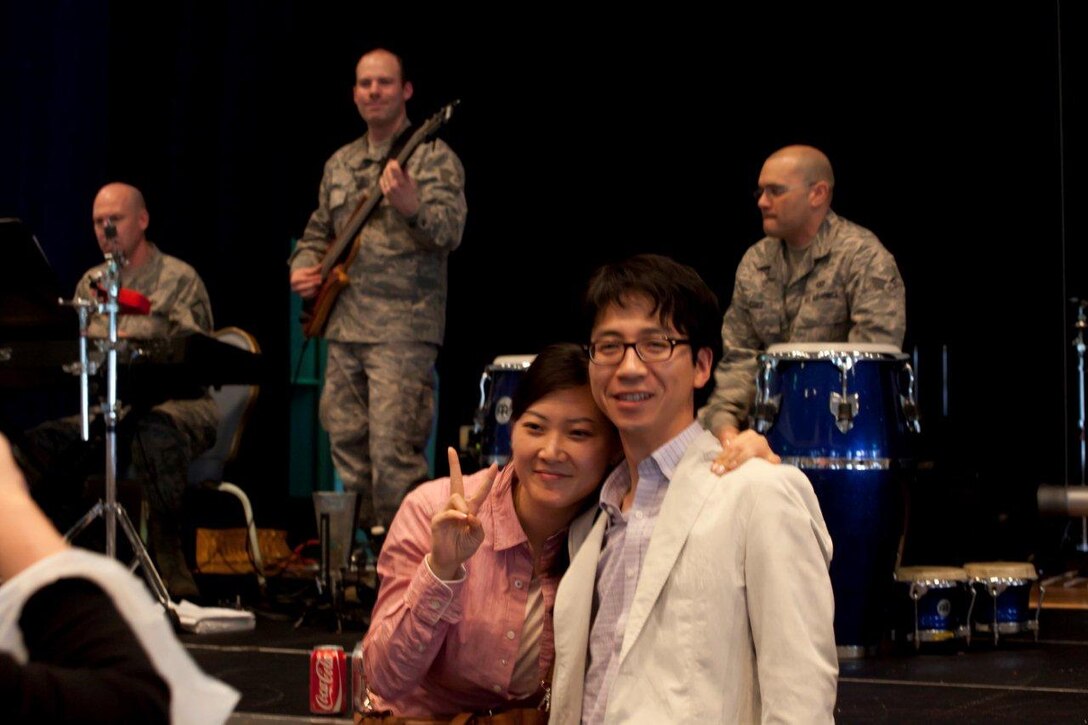 A young couple finds an opportunity to smile in a difficult time, then
and strike a pose, bringing a smile to the bass player SSgt Mike Schmaus.
SrA Freddie Cruz engages other passengers while performing a rhythmic solo
on the Congas. (Courtesy photo)

