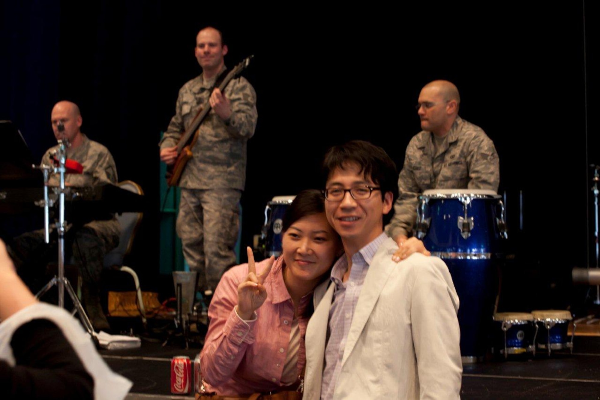 A young couple finds an opportunity to smile in a difficult time, then
and strike a pose, bringing a smile to the bass player SSgt Mike Schmaus.
SrA Freddie Cruz engages other passengers while performing a rhythmic solo
on the Congas. (Courtesy photo)


