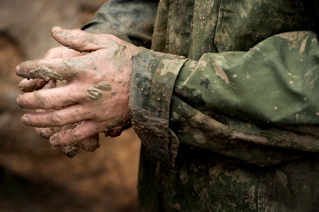 Air Force Staff Sgt. Justin England wipes mud from his hand after spending several hours repairing a broken water main on Whiteman Air Force Base, Mo., March 7, 2011. England is a maintenance specialist assigned to the 509th Civil Engineer Squadron.