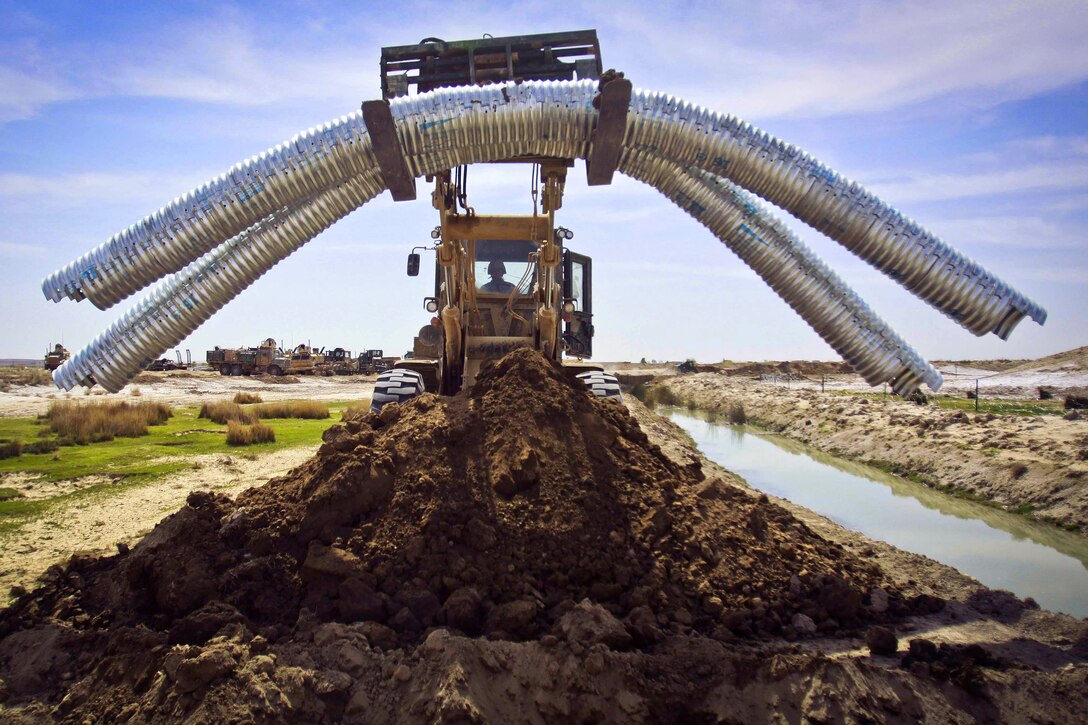 U.S. Marine Corps combat engineers and heavy equipment operators use heavy equipment vehicles to install metal culverts during a civil development project in Haji Hanif Khan, Afghanistan, March 11, 2011.