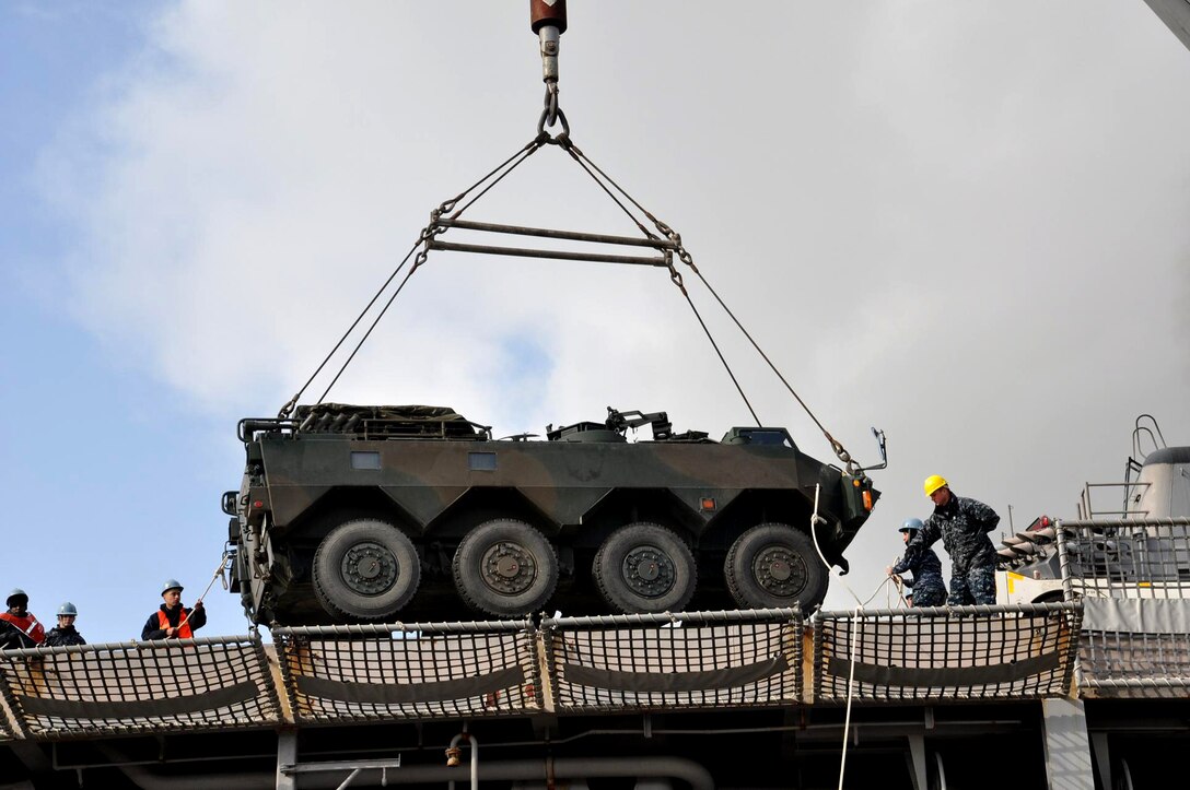 U.S. Navy Petty Officer 2nd Class Dante Galati directs the loading of more than twenty Japanese armored trucks onto the USS Tortuga in Tomakoman-Ko, Japan, March 15, 2011. The Tortuga is in Tomakoman-Ko to collect Japanese military personnel and supplies to support earthquake and tsunami relief efforts.