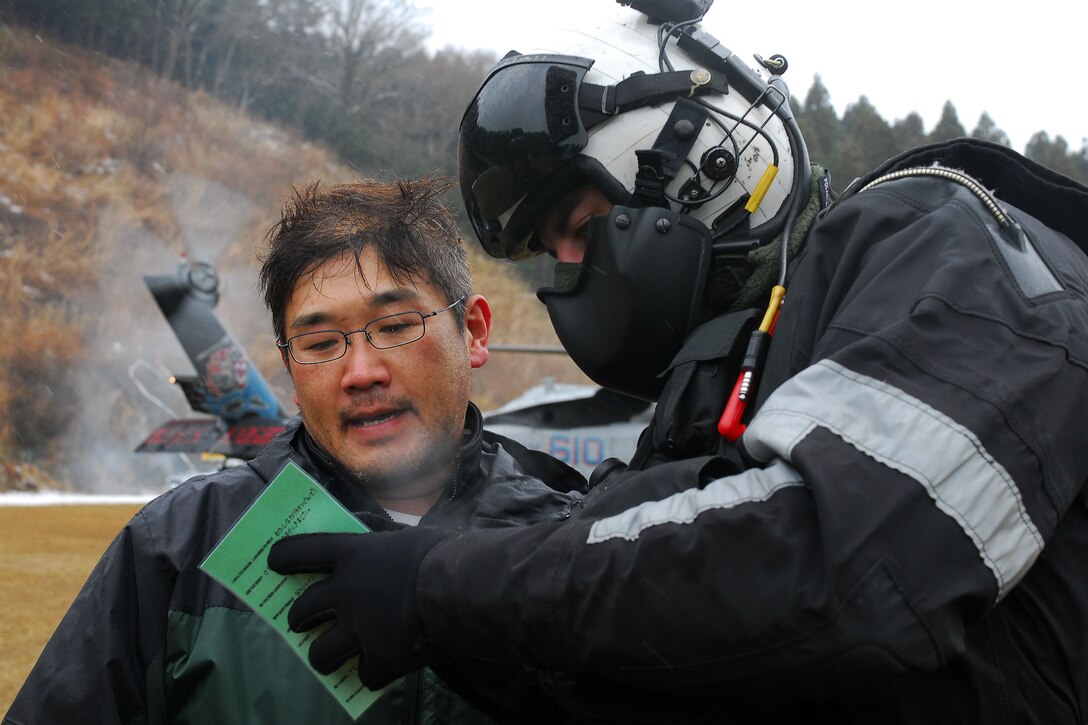 U.S. Navy Seaman Chris Tautkus uses a translation card to ask a Japanese citizen if he needs additional supplies and assistance in Kuro-Soki, Japan, March 16, 2011. Tautkus is an air crewman assigned to Helicopter Anti-Submarine Squadron 4, which is providing humanitarian assistance to Japan to support Operation Tomodachi. 