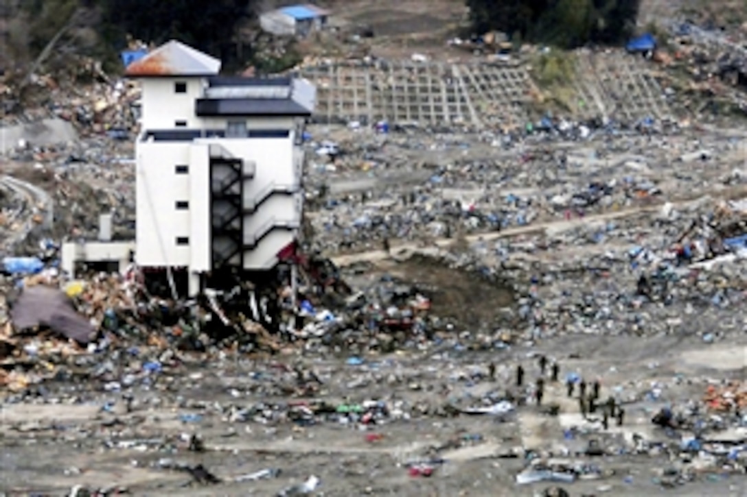 A Japanese search and rescue team searches the rubble near a high-rise building in Wakuya, Japan, March 15, 2011, after an 8.9-magnitude earthquake and tsunami devastated the area. Ships and aircraft from the Ronald Reagan Carrier Strike Group are conducting search and rescue operations and re-supply missions to support Operation Tomodachi throughout northern Japan.