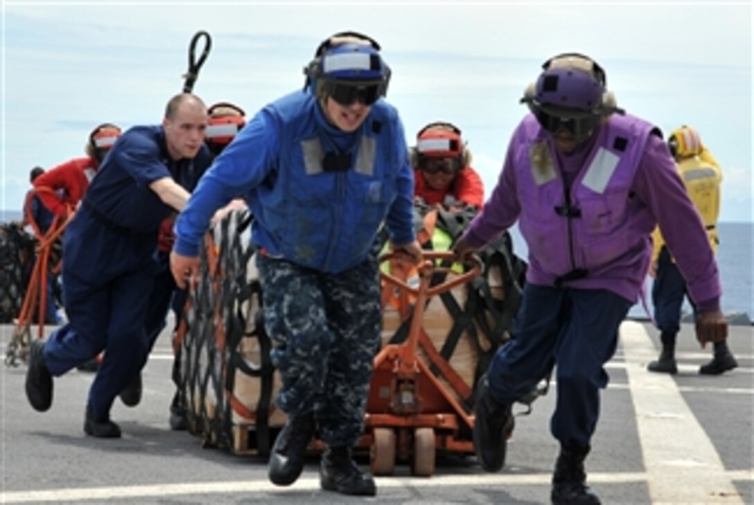 U.S. Navy sailors aboard the U.S. 7th Fleet flagship USS Blue Ridge (LCC 19) move pallets of humanitarian assistance/disaster relief kits across the shipís flight deck during an underway replenishment with the fleet replenishment oiler USNS Rappahannock (T-AO 204) in the South China Sea on March 12, 2011.  The Blue Ridge loaded the kits to ensure the crew was ready to provide assistance in support of earthquake and tsunami relief operations in Japan as directed.  