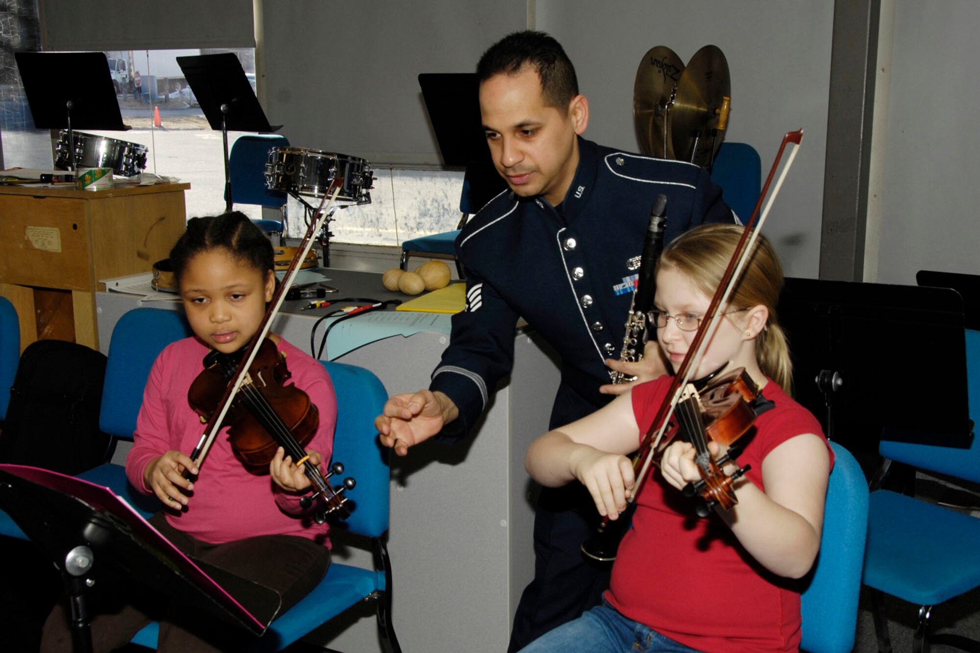 HANSCOM AIR FORCE BASE, Mass. - Staff Sgt. Matthew Ayala-Roman (center), a clarinetist with the Air Force Band of Liberty, teaches violin lessons to Jeannelle Green and Phoebe Delory at Hanscom Middle School on March 8. Members of the Band of Liberty’s Bay State Winds ensemble visited the school to teach lessons to a music class and then presented a concert to all students afterwards. (U.S. Air Force photo by Linda LaBonte Britt) 