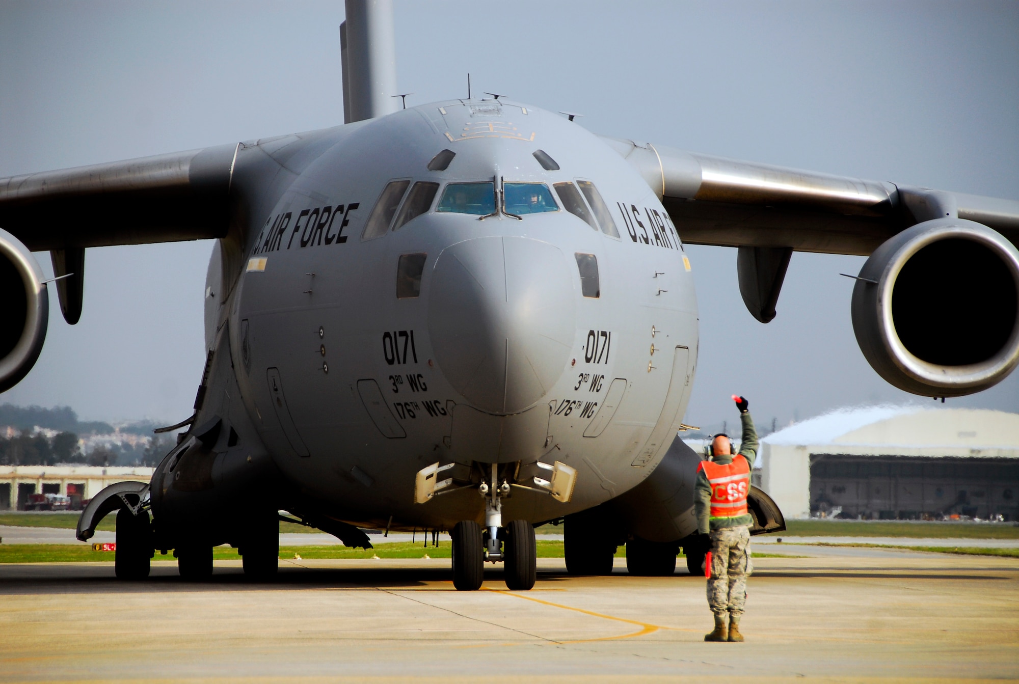 Staff Sgt. Jay Steppat, 733rd Air Mobility Squadron electro environmental craftsman, marshals in a Joint Base Elmendorf-Richardson C-17 Globemaster III on the Kadena Air Base flight line, March 17. The C-17 crew from JBER loaded Japan Ground Self Defense Force personnel and equipment into the aircraft to take to mainland Japan for the disaster relief effort. (U.S. Air Force photo/Airman 1st Class Maeson L. Elleman)