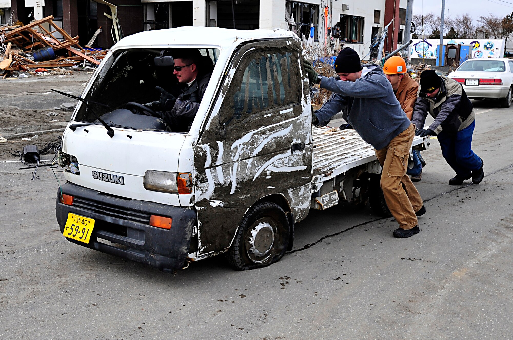 MISAWA AIR BASE, Japan -- Airmen push an abandoned vehicle to the side of the road at the Misawa City port Mar. 15. Airman and Sailors are urged to volunteer their time to help the local community.  (U.S. Air Force photo by Staff Sgt. Marie Brown\Released)
