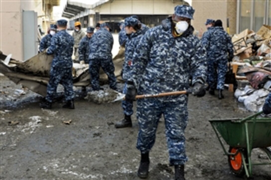 U.S. Navy Petty Officer 2nd Class Robert Bannister removes mud sediment from behind a damaged building in Hachinohe, Japan, March 17, 2011. Sailors from Naval Air Facility Misawa and its tenant commands are assisting with cleaning up the tsunami-damaged city. Bannister is a logistics specialist assigned to Fleet and Industrial Supply Center Misawa.