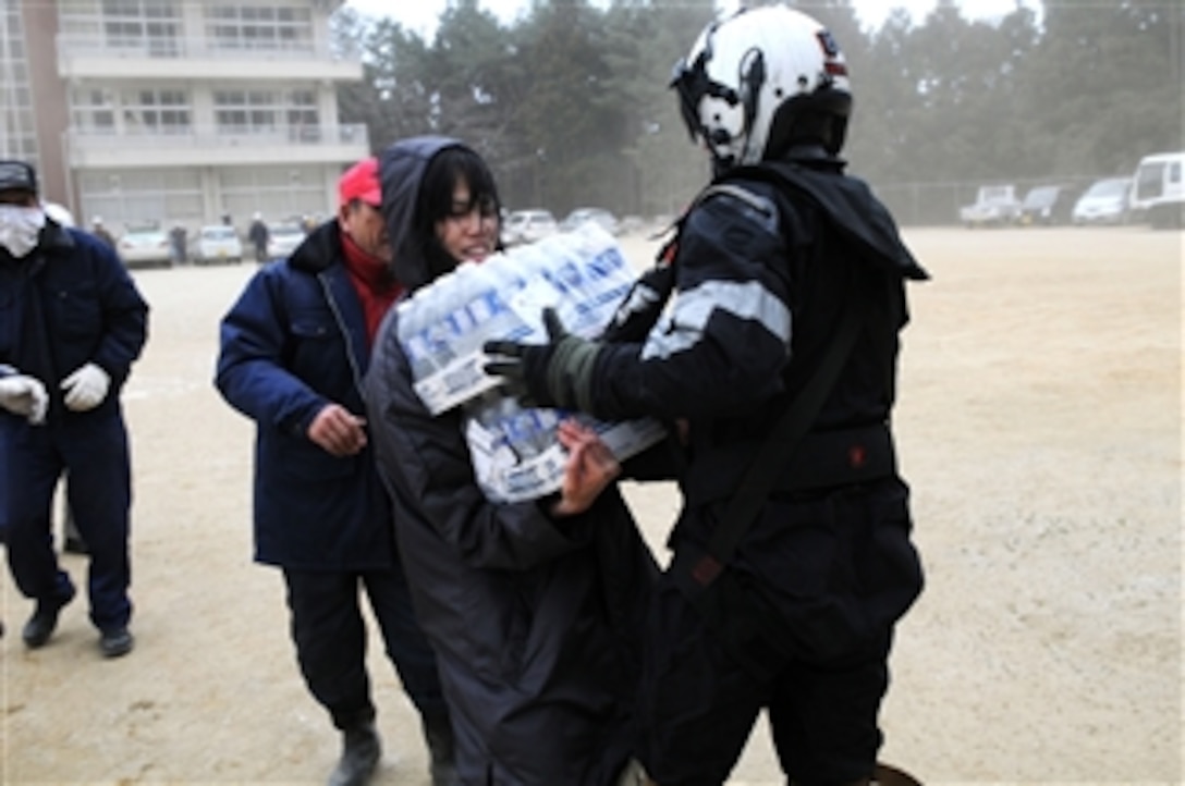 Petty Officer 2nd Class Zack DelCorte, assigned to Helicopter Anti-Submarine Squadron 4 embarked aboard the aircraft carrier USS Ronald Reagan (CVN 76), hands bottled water to a Japanese citizen in northern Japan on March 15, 2011.  The squadron is delivering humanitarian supplies to areas affected by an earthquake and subsequent tsunami.  Ships and aircraft from the Ronald Reagan Carrier Strike Group are conducting search and rescue operations and re-supply missions as directed in support of Operation Tomodachi throughout northern Japan.  