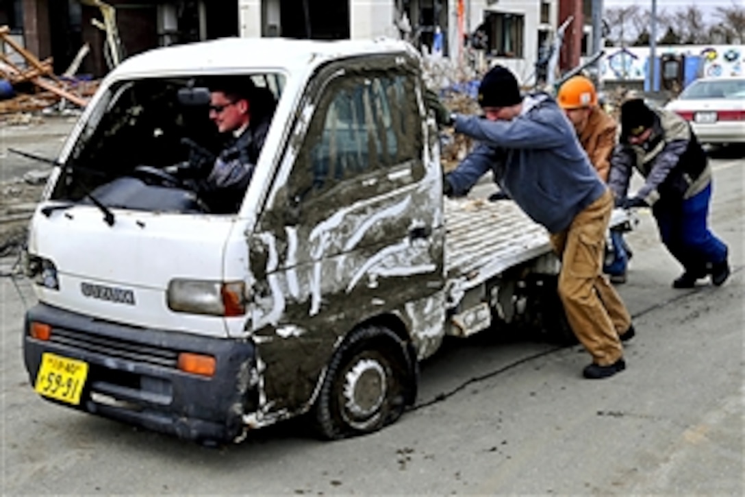 U.S. Air Force airmen push an abandoned vehicle to the side of the road in Misawa, Japan, March 15, 2011, following a recent 8.9-magnitude earthquake and tsunami. The airmen are assigned to Misawa Air Base.