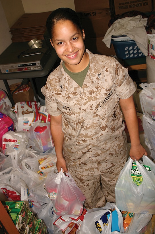 Lance Cpl. Yamile Brito is surrounded March 18 by the food donations from a canned food drive she coordinated at the Camp Courtney commissary. Brito said she started the food drive becasue she needed some way to help the Japanese victimes of the 9.0 magnitude earthquake and resulting tsunami that struck mainland Japan March 11. The canned food drive at the Camp Courtney commissary is scheduled to continue through March.