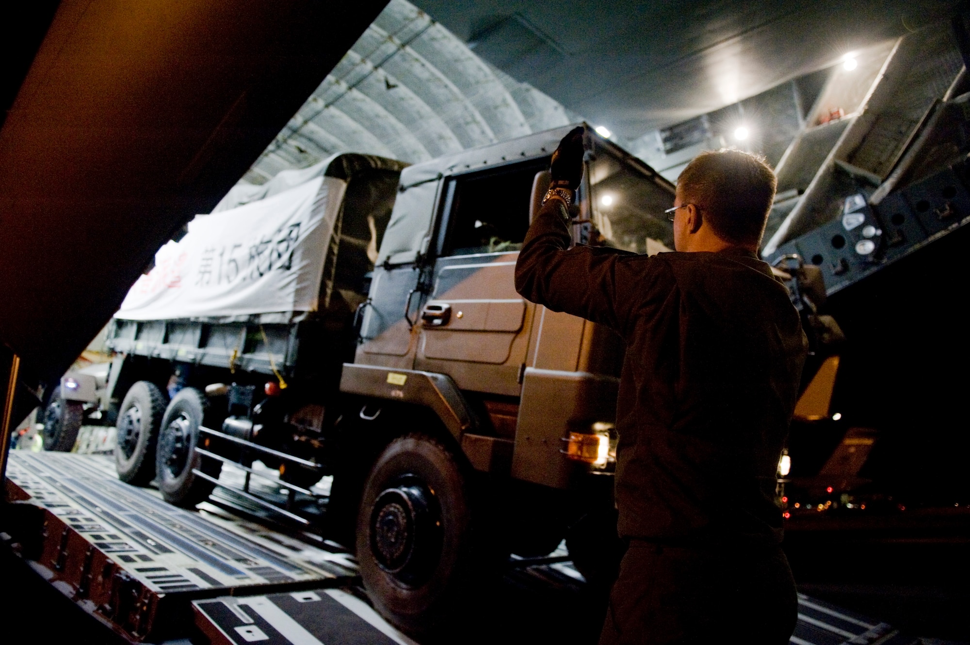 YOKOTA AIR BASE, Japan -- Royal Australian Air Force Senior Master Sgt. Chris Voight, guides a Japan Ground Self Defense Force vehicle off a C-17 Globemaster III here March 18. The RAAF transported the JGSDF 15th Brigade from Okinawa to help with Japan's earthquake and tsunami relief effort. (U.S. Air Force photo/Staff Sgt. Jonathan Steffen)