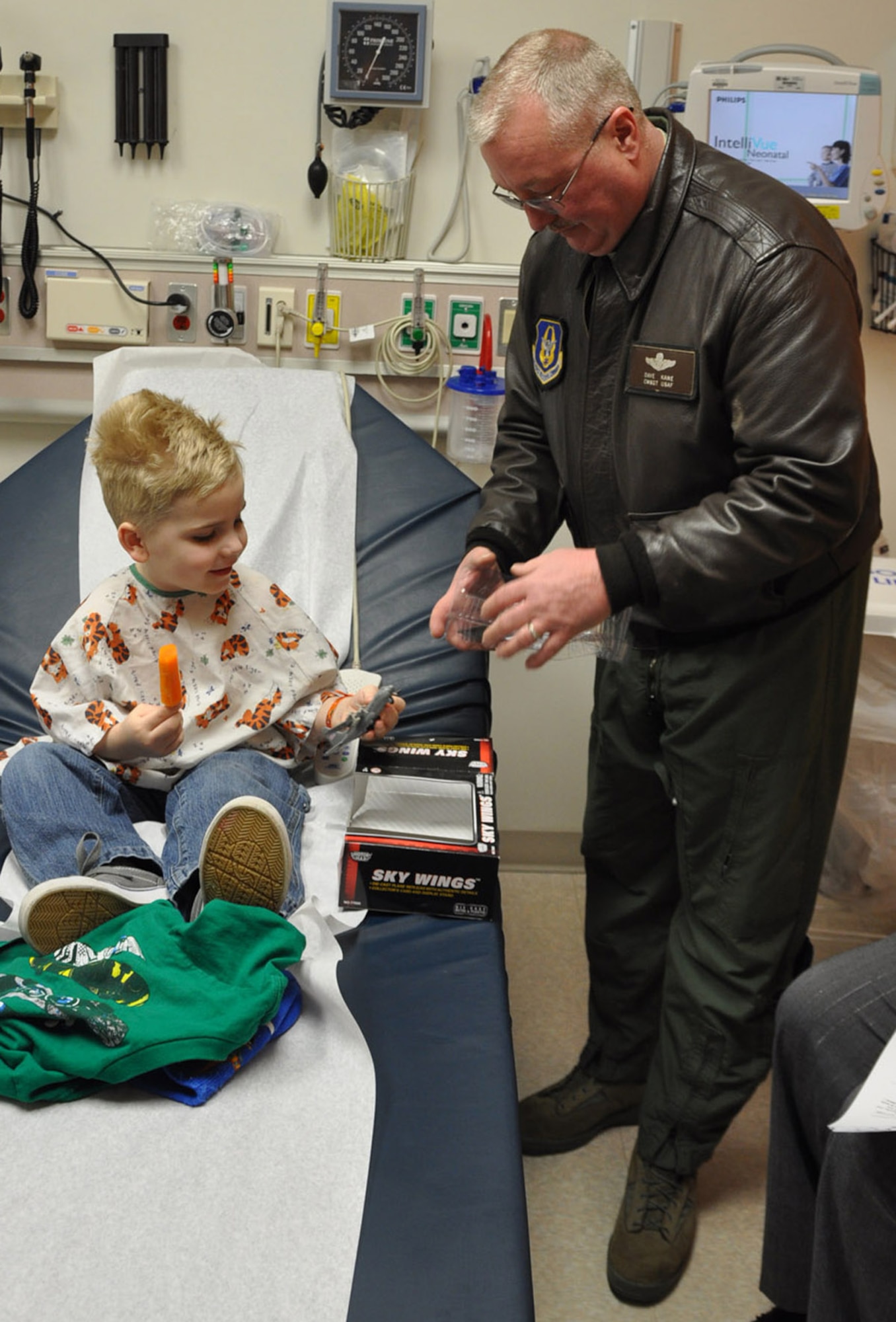 BOARDMAN, Ohio — Air Force Reservist Chief Master Sgt. Davis Kane, a Chief Flight Engineer withthe 910th Airlift Wing helps unwrap a toy C-130 for four-year old Michael Keyes at Akron Children's Hospital of the Mahoning Valley on St. Patrick's Day, March 17.  Chief Kane was one of four Citizen Airmen visitng children at the medical facility.  Dozens of diecast metal C-130 toy airplanes were given to children receiving treatment at the Boardman medical campus.  The toys were funded by the Youngstown Air Reserve-Base Community Council. Michael is a patient at the Boardman campus.  U.S. Air Force Photo/ Maj. Brent Davis