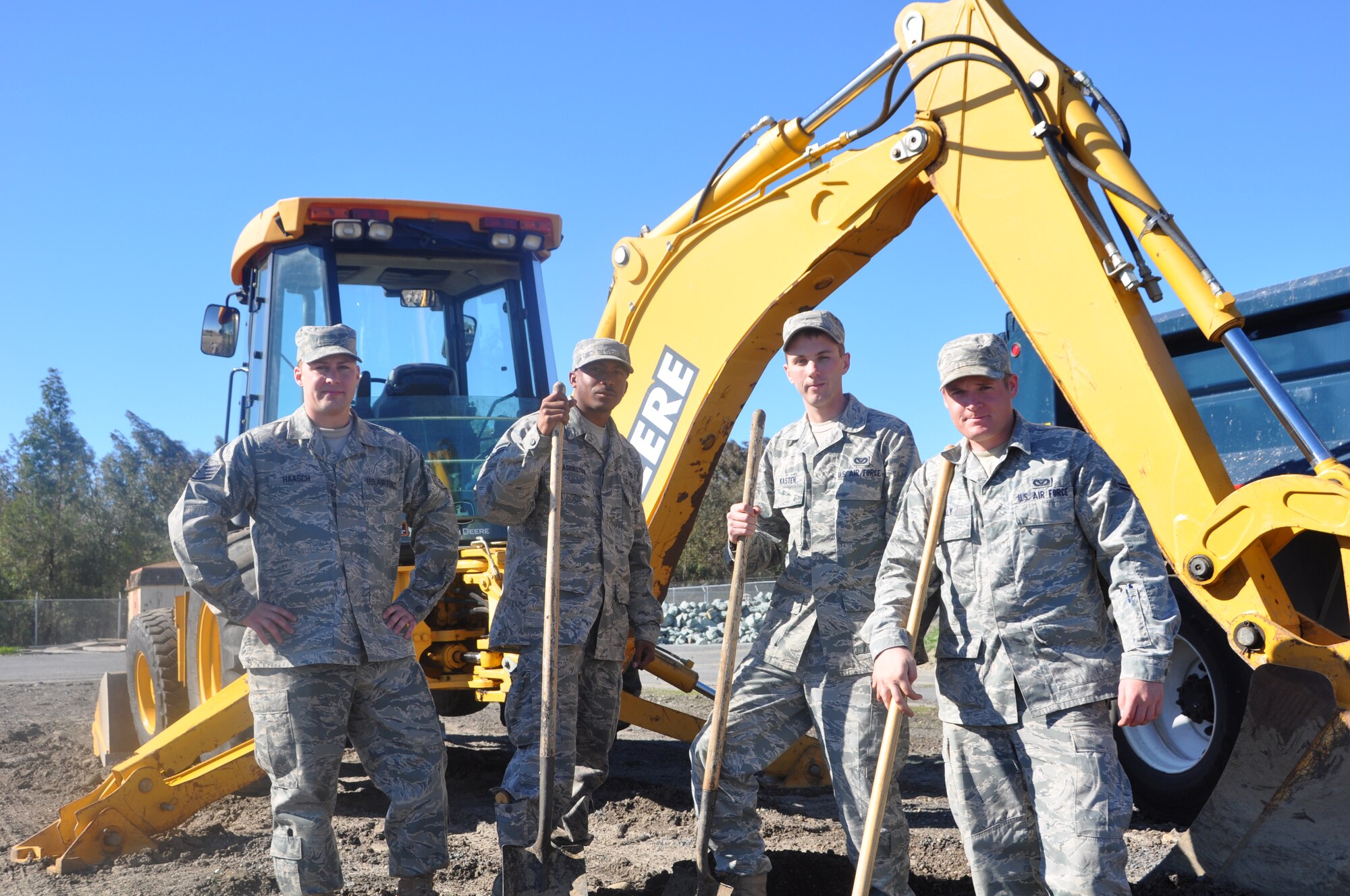 Staff Sgt. Nicholas Haasch, Senior Airman Duron Washington, Senior Airman Darren Kasten and Senior Airman Evan Daly - "the dirt boys" - pose recently next to a backhoe.