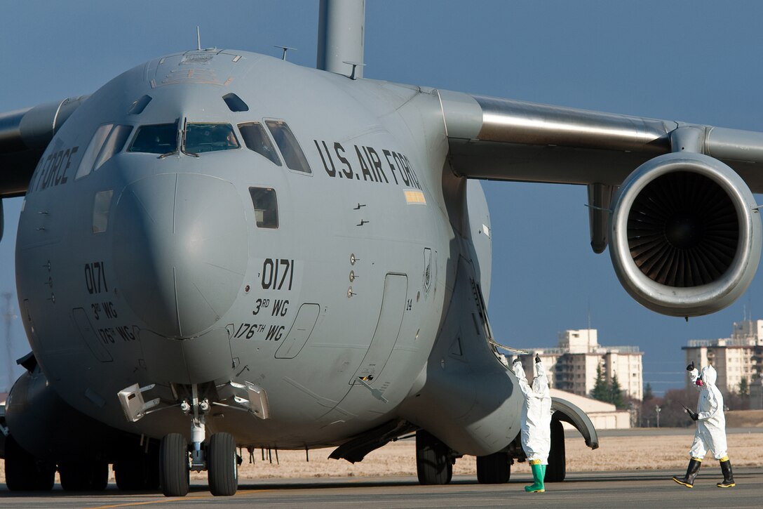 Senior Airman Eva Gaus (left) and Senior Airman Jonathan Jones (right) indicate "all clear" to a pilot after checking for beta and gamma radiation March 17, 2011, at Yokota Air Base, Japan. The C-17 Globemaster III transported Japan Ground Self Defense Force troops and vehicles here from Okinawa, to support the relief effort after the earthquake and tsunami, March 11. Airmen Gaus and Jones are assigned to the 374th Civil Engineer Squadron. (U.S. Air Force photo/Osakabe Yasuo) 