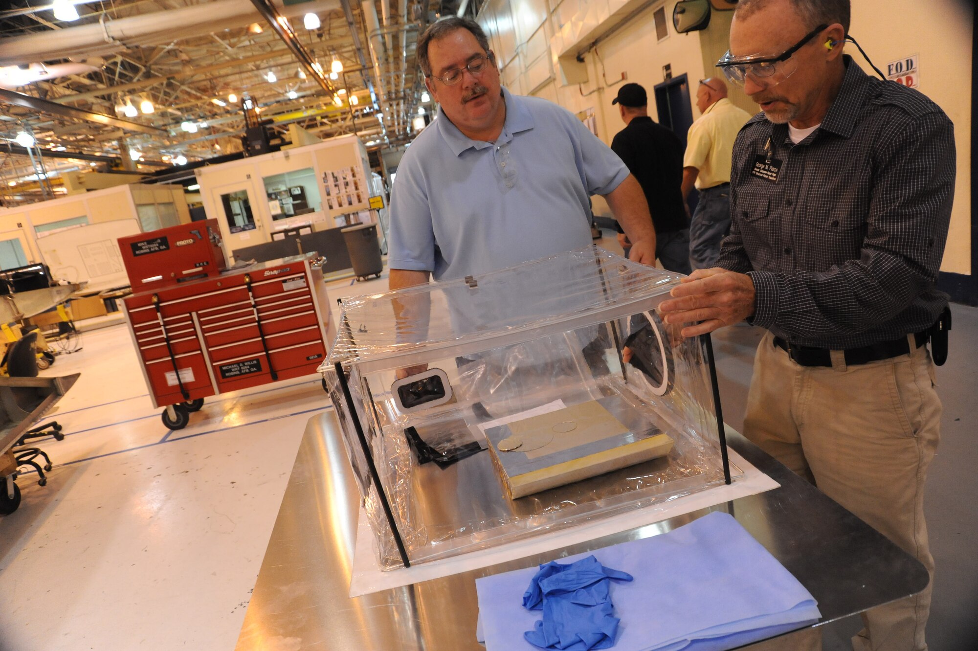 George Pierce, right, 574th Composite Repair Flight director, and Ray Fisher, sheet metal worker; discuss advantages of containment bags. Called "Dirt Bags," they help reduce dust migration. U. S. Air Force photo by Ray Crayton Jr.