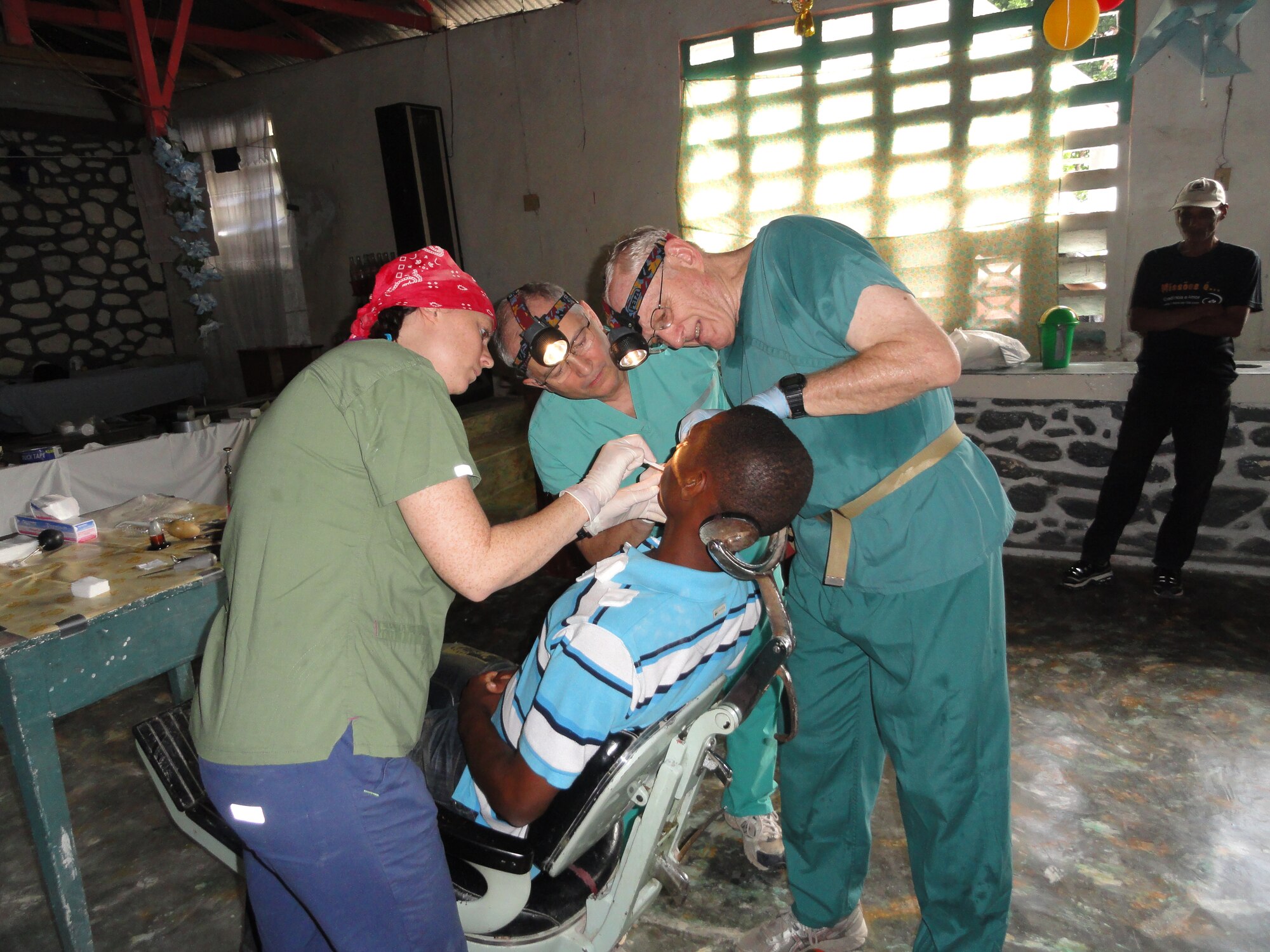 1st Lt. Carli Brown (left) assists her father Lt. Col. (Dr.) Victor Brown and Dr. John Nystrom perform a dental procedure on a young Haitian boy near the Haitian capital of Port-Au-Prince. Both the Browns and Dr. Nystrom travel down to Haiti as part of the Weslyan Medical Fellowship to provide medical and dental relief to the Haitian people. (Courtesy photo)