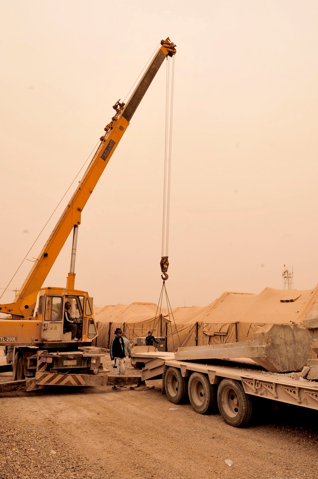 Not even a sand storm in the Iraqi desert stops the removal of concrete T-wall barriers March 3, 2011, at Victory Base Complex in Baghdad. U.S. government officials have turned over 80 installations and facilities to the Government of Iraq under the current security agreement. Each T-wall section weighs 6 tons and is 12-feet tall. (U.S. Air Force photo/Senior Master Sgt. Larry Schneck) 

