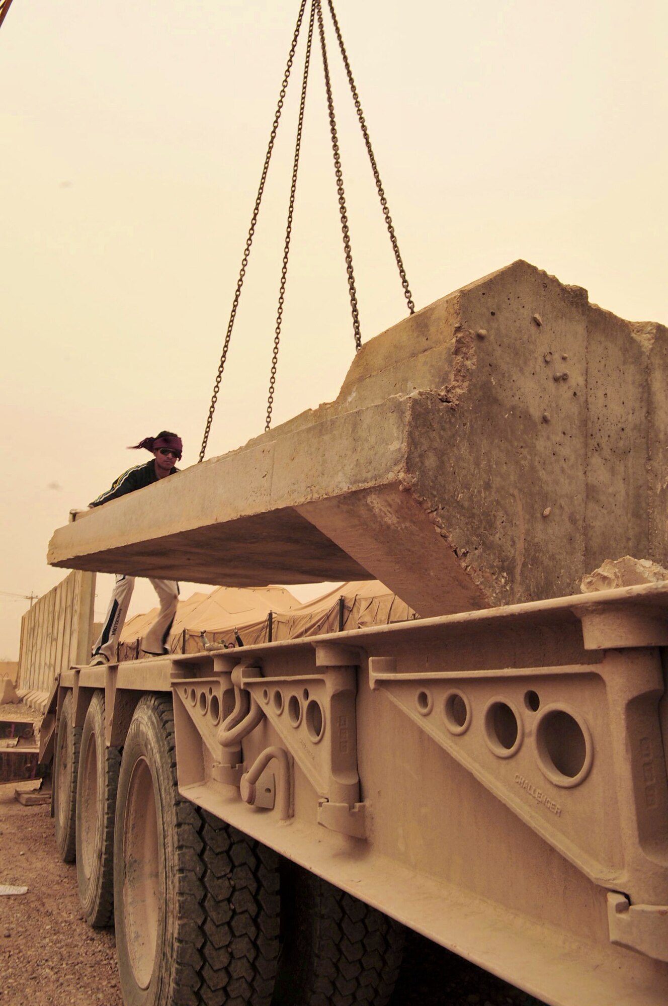 In the middle of an orange haze during a sand storm in the Iraqi desert, an Iraqi contractor rigs a T-wall concrete barrier onto a flatbed truck, March 3, 2011, at Victory Base Complex in Baghdad. The local-national contractor is supporting a partnered effort to turn-over 1,200 U.S. forces T-walls to the Iraqi army. A T-wall section weighs 6 tons and is 12-feet tall. (U.S. Air Force photo/Senior Master Sgt. Larry Schneck) 