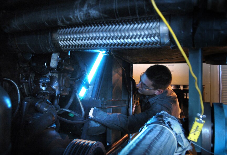 Airman 1st Class Alex Coughlin, Aerospace Ground Equipment Journeyman, sets up his work light before he starts removing a Power Take-Off adapter on a Air Conditioning and Heating supply unit. (Air Force photo by Micah Garbarino)