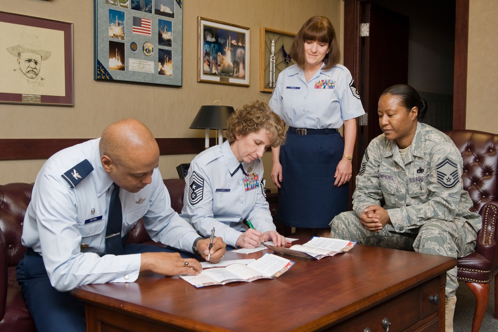 Brig. Gen. (Sel) Anthony Cotton, 341st Missile Wing Commander and Chief Master Sgt. Cari Kent, 341st Missile Wing Command Chief, sign their Air Force Assistance Fund pledge forms, March 7. Master Sgt. Jane Pullo, 341st Security Forces Group, Knowledge Operations superintendent and Senior Master Sgt. Kimberly Thompkins, 341st Logistics Readiness Squadron Deployment and Distribution superintendent, look on. (U.S. Air Force photo/Beau Wade)