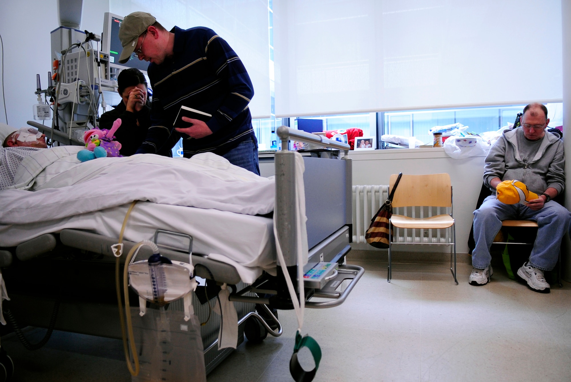 Army Chaplain (Capt.) Andrew Shriver, U.S. Army Garrison Wiesbaden, Germany, says a prayer with Staff Sgt. Kris Schneider, his wife Amanda and his father Bruce at the Johann Wolfgang Goethe University Hospital in Frankfurt am Main. The 48th Security Forces Squadron Airman from RAF Lakenheath, United Kingdom, was being treated for injuries sustained during the March 2, 2011, shooting at the Frankfurt International Airport. (U.S. Air Force photo by Tech. Sgt. Jocelyn L. Rich)