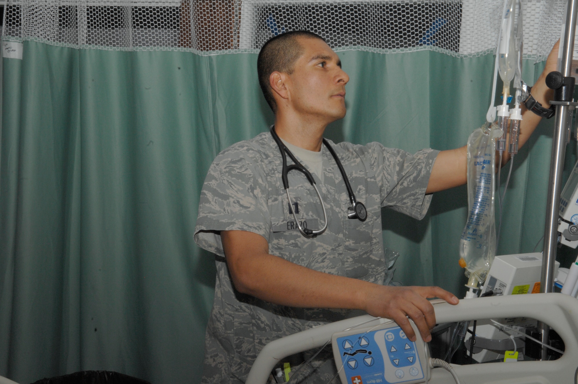 Capt. Hernan Erazo, Craig Joint Theater Hospital critical care nurse, checks the fluids on a patient in the intensive care unit. Captain Erazo is deployed from Langley Air Force Base, Va.(U.S. Air Force photo/Senior Airman Amber R. Kelly-Herard)