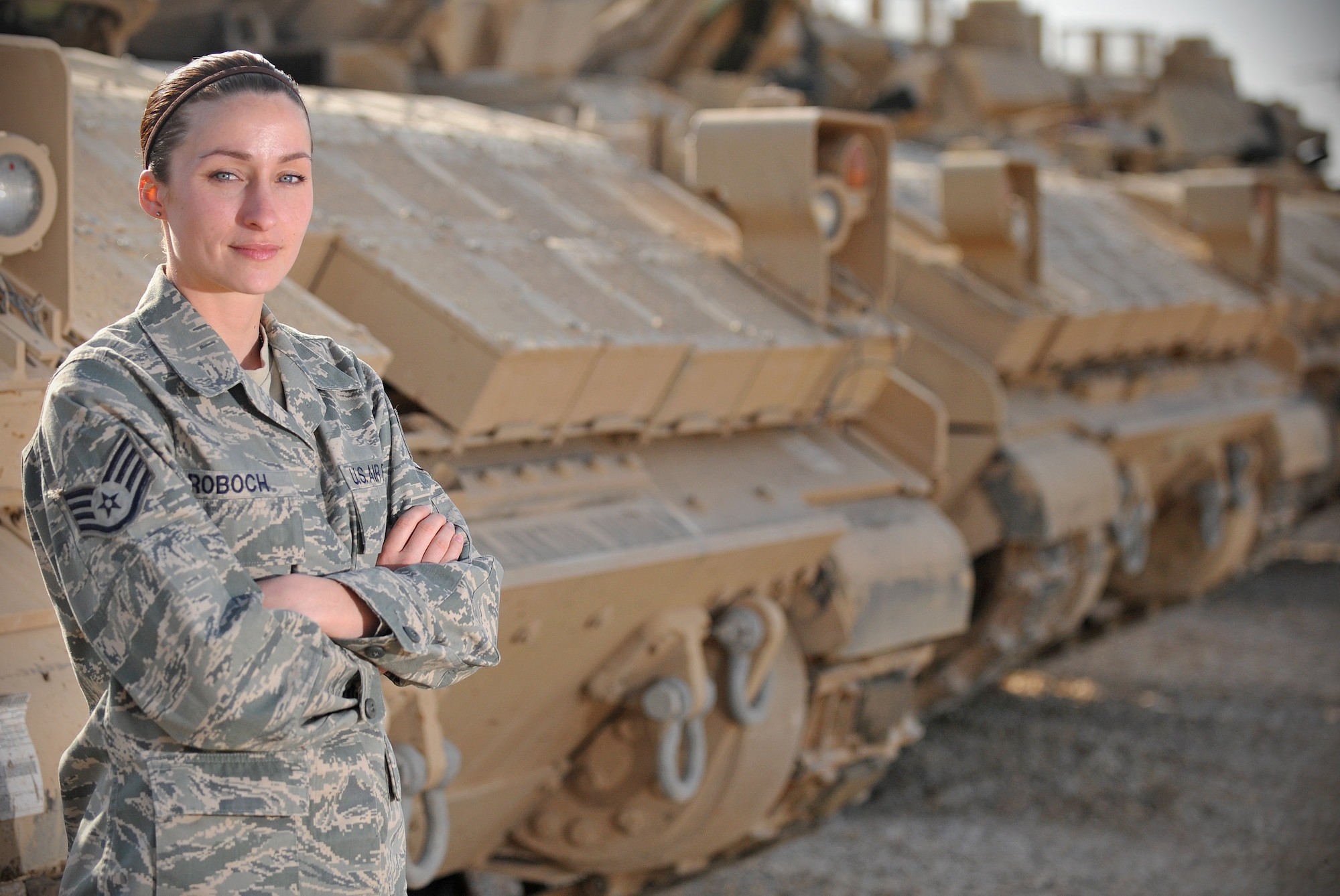 Staff Sgt. Esther Roboch, Tallil redistribution property assistance team's rolling stock NCO in charge, poses for a photo in front of a row of Bradley tanks March 5, 2011, at Ali Air Base, Iraq. Sergeant Roboch is a native of Jacksonville, Fla. (U.S. Air Force photo by Senior Airman Andrew Lee/Released) 
